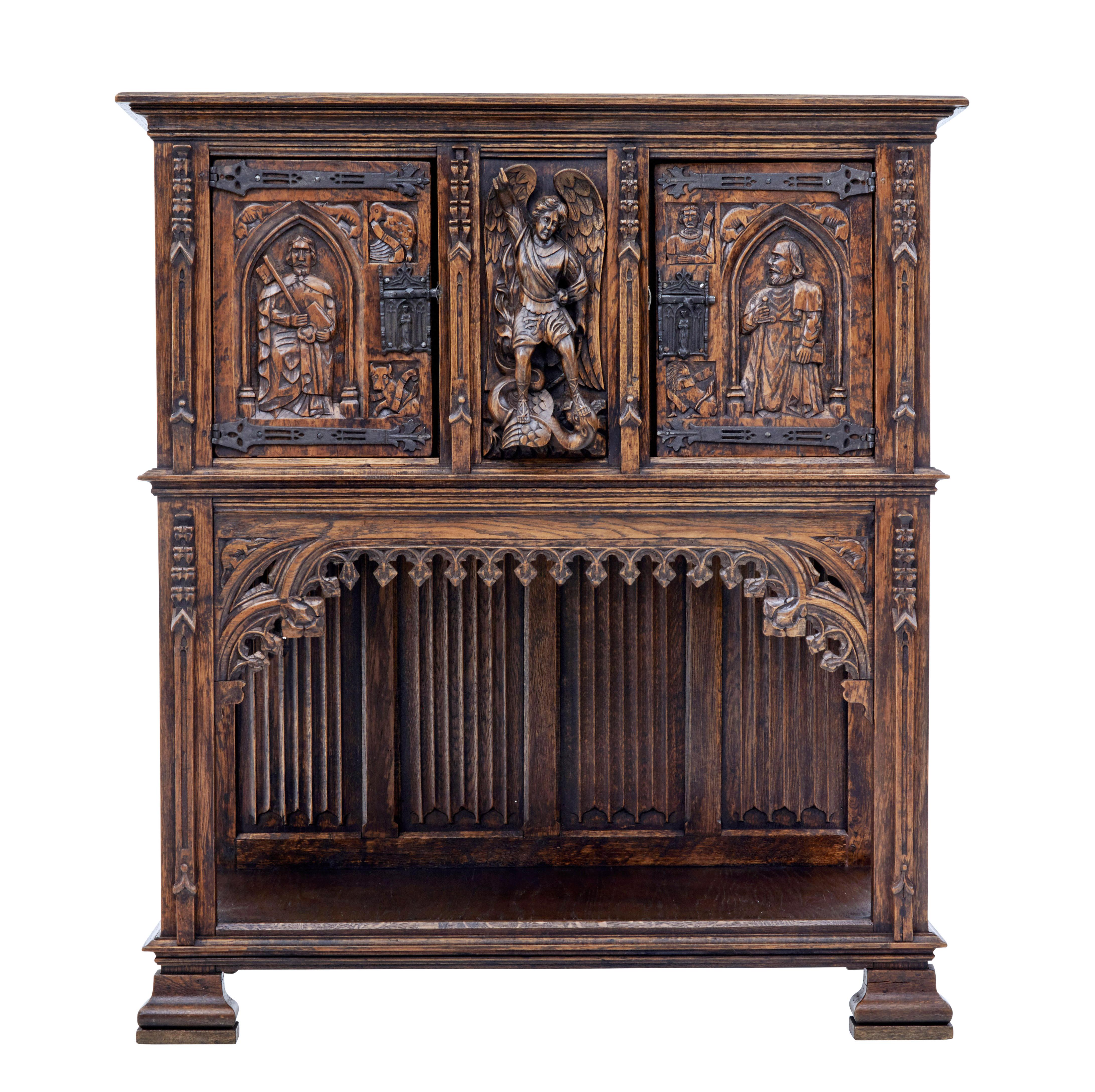 Impressive 1 piece carved oak buffet, circa 1890.

Central carved oak panel depicting an angel, flanked either side by a single door cupboard with carved religious figures. Original hinges and cast decorative locks.

Below the cupboard is a