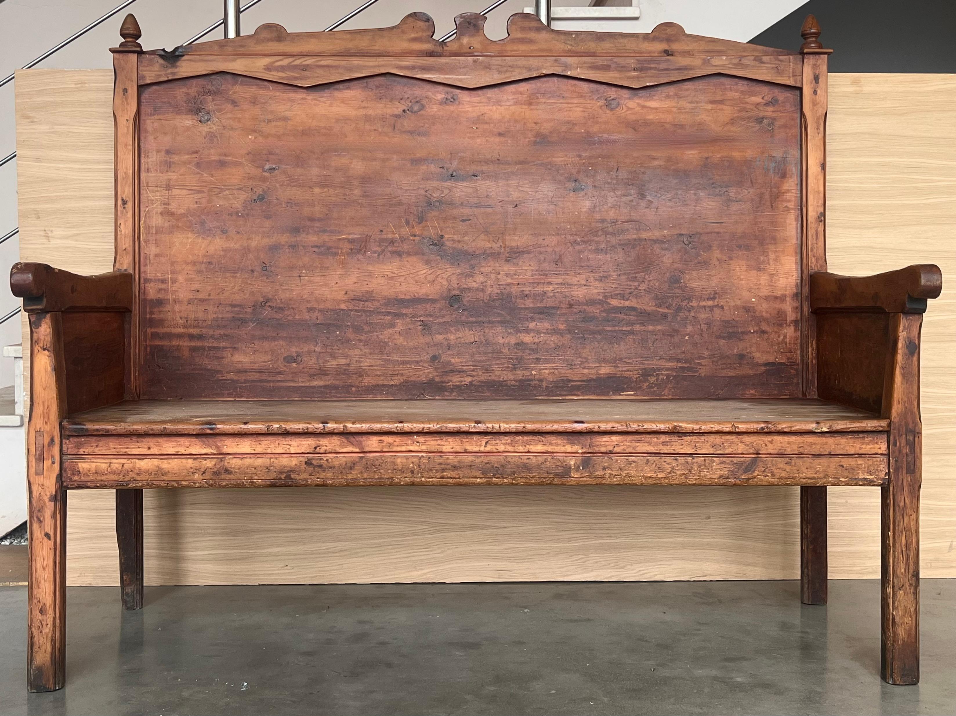 A late 19th century primitive settle bench handcrafted in the Catalan region of Spain of mélèze, a hard pine grown in mountainous regions, circa 1850s. Having a carved scalloped wing back and scalloped apron, this handsome Spanish bench features