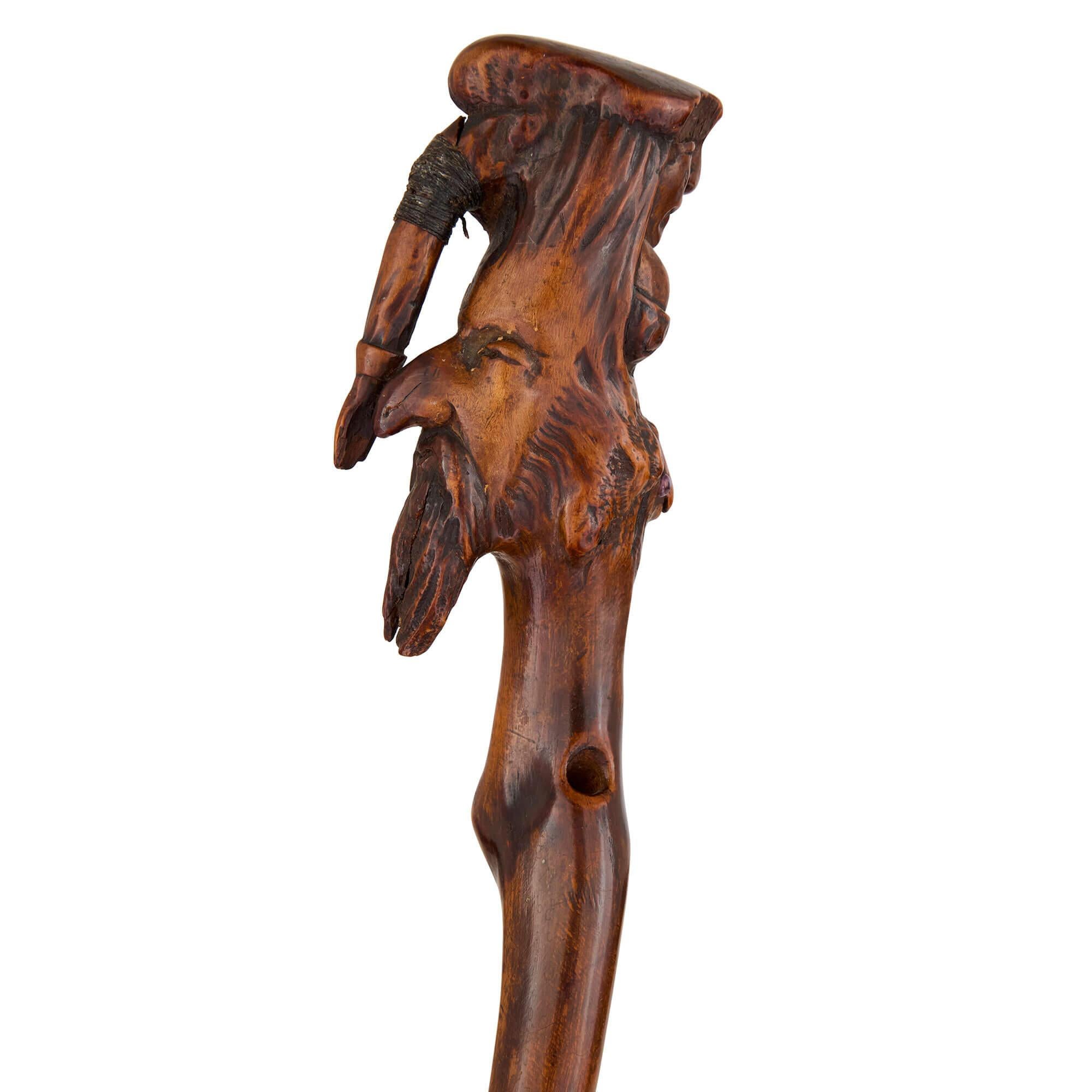 Canne d'art populaire en bois sculpté de la fin du 19e siècle 
Continental, Fin du 19e siècle  
Hauteur 89 cm, largeur 6 cm, profondeur 4 cm  

Cette canne antique, sculptée à la main dans du bois, présente un design frappant et distinctif. 

Au