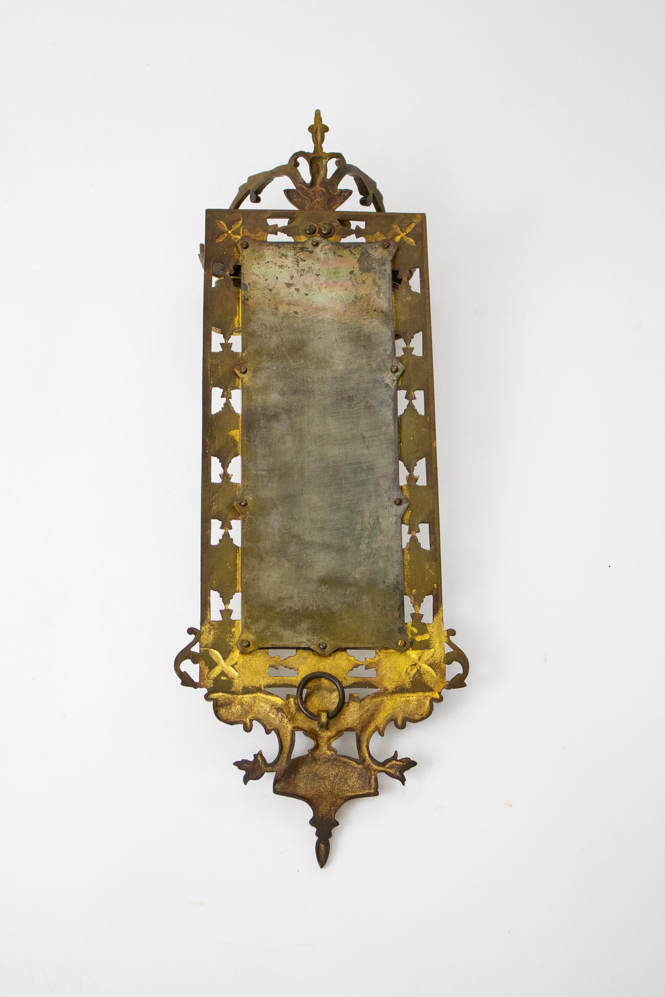 A classic mirrored sconce, rectangular in form. The top ornament features two classical dolphins. Two arms at the bottom to hold taper candles. The mirror is beveled, and has age spots in the original backing. The brass has an aged patina and has