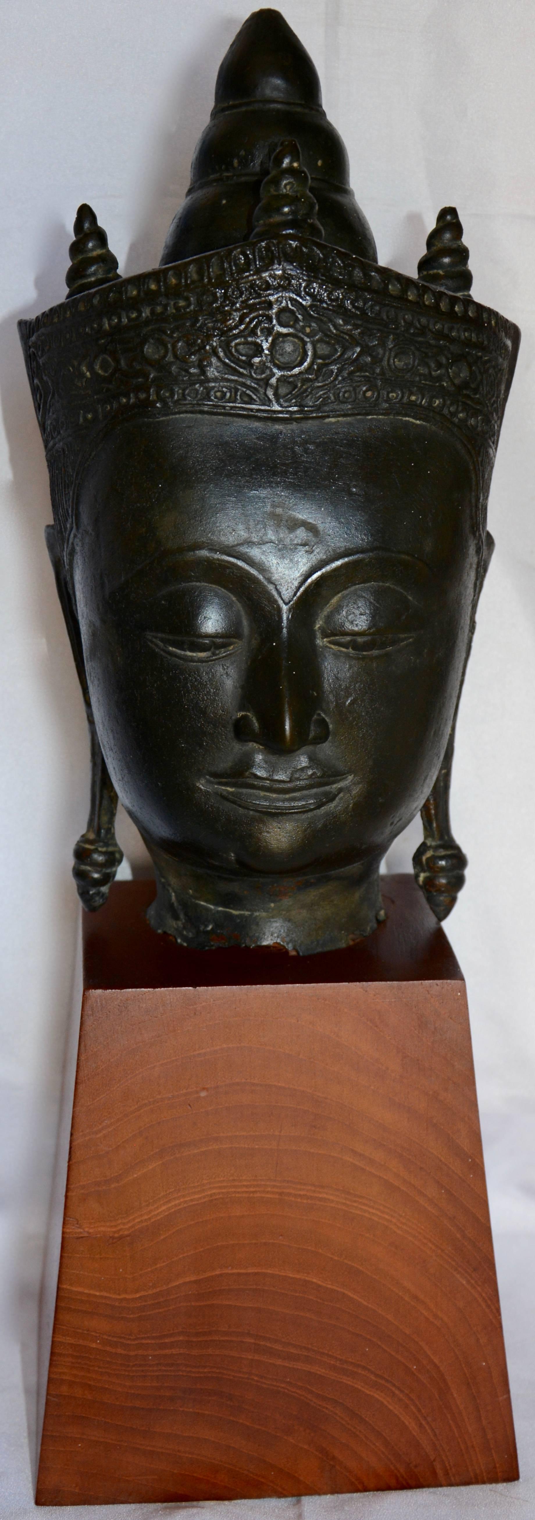 Featured is a fabulous cast bronze Thai Buddha bust statue mounted on a wooden base. It has the features of a traditionally designed Buddha statue, including stylized crown and elongated earlobes. The bronze head is hollow, and the neck fits over a