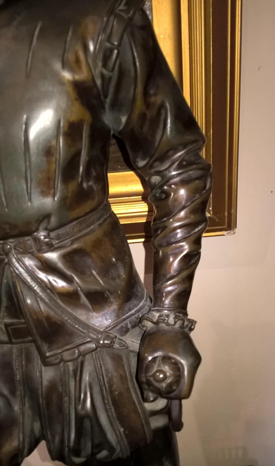 An unsigned decorative late 19th century cast bronze standing figure of a youth attired in the manner of a Shakespearean character.
One hand holding the handle of a sword, the blade of the sword is missing. 
 