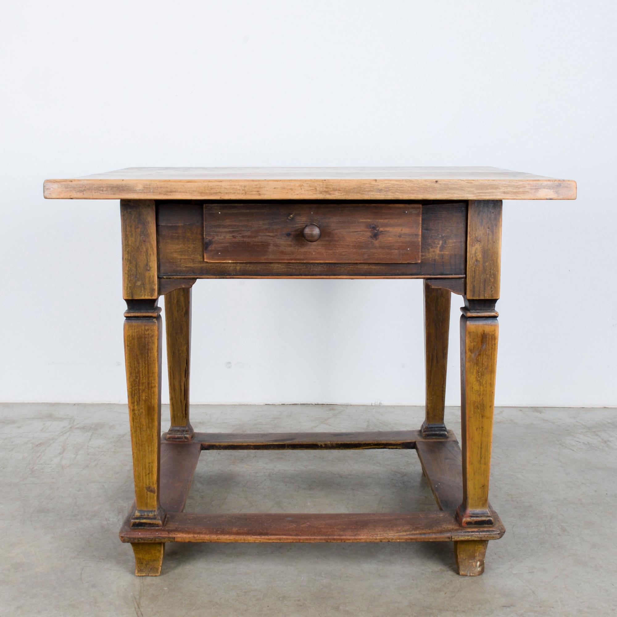 A wooden table with a drawer from Czechia, circa 1880. A harmonious form, based on repeating squares: a stout tabletop is echoed by square embellishments on the legs, and a low square frame that sits just above the feet. The gentle curve of the feet