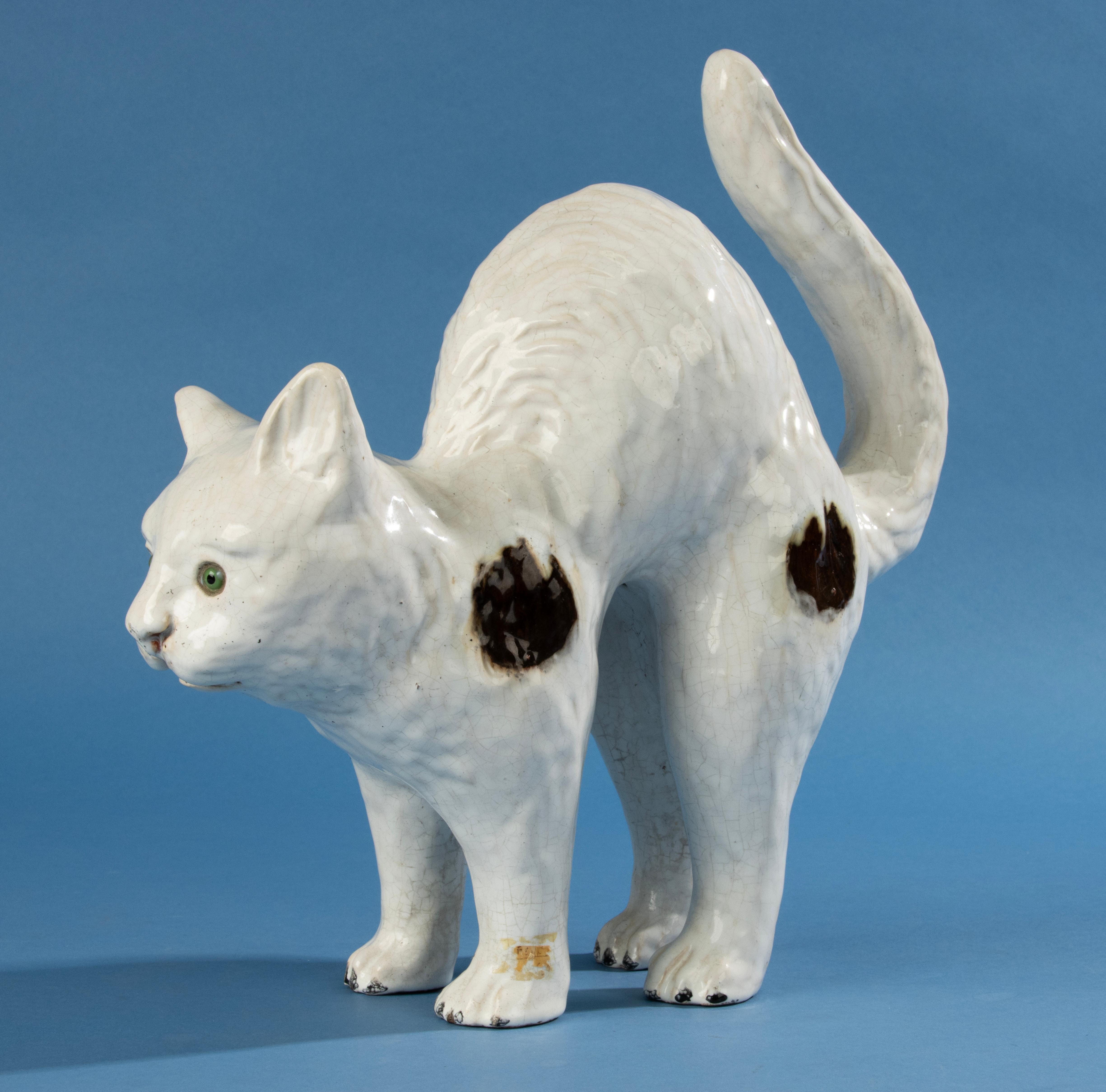 Eine schöne Keramikkatze, die wahrscheinlich von dem französischen Hersteller Mesnil de Bavent hergestellt wurde. Die Katze ist aus Terrakotta gefertigt und hat eine schöne Zinnglasurschicht mit klarem Craquelé. Die Katze hat Glasaugen.
Die Skulptur