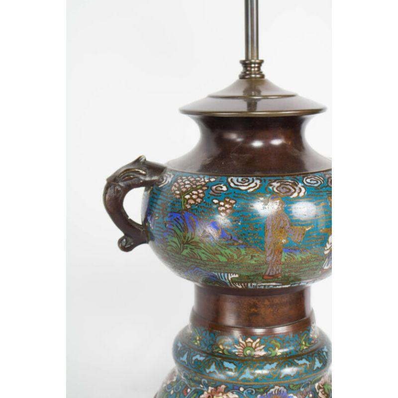 Champleve table lamp. Features a country scene with three people and lotus flowers around the base. Damage to center middle. Price reflects damage. Lamp would be priced $1450 if in excellent condition

Material: bronze, enamel
Style: Asian