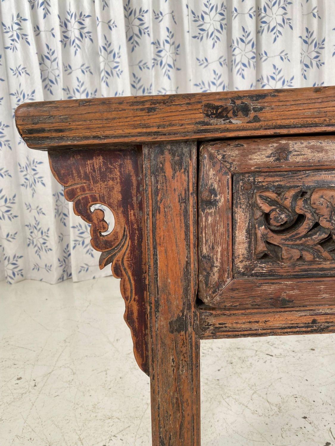 A late 19th-century Chinese Alter table. This Alter table features a deeply carved drawer front with the original metal drop pull handle. The drawer has a leaf pattern and dovetail joinery. This table was most recently purchased from CC Wong in