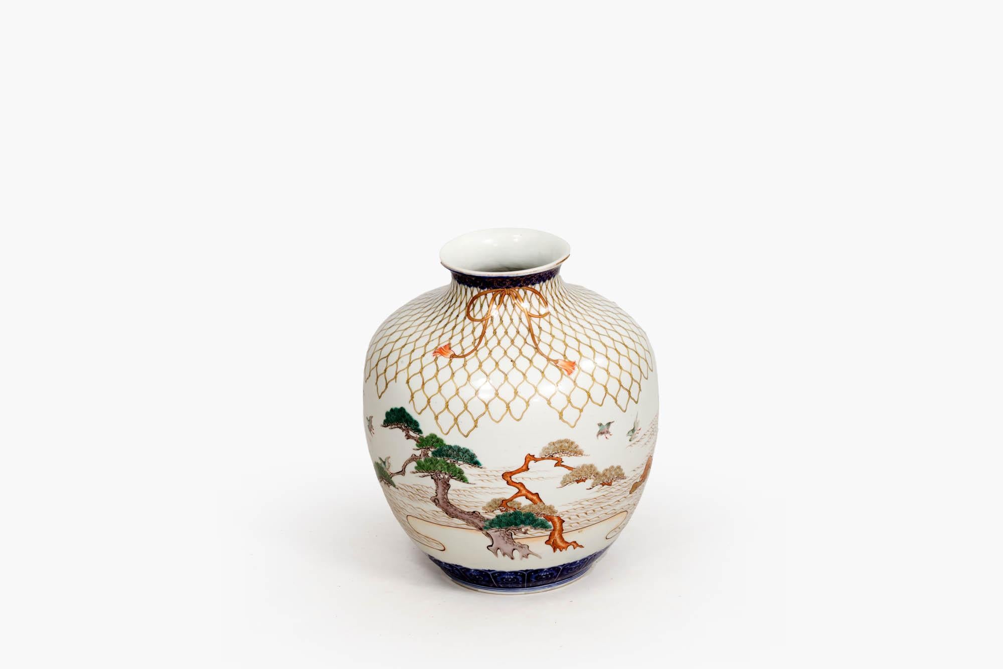 Late 19th century Chinese ceramic vase in the Japanese style, bulbous in shape with painted naturalistic detailing of trees, water, and birds. Solid deep blue banding highlights the neck and lower section towards the base, with a delicate hand