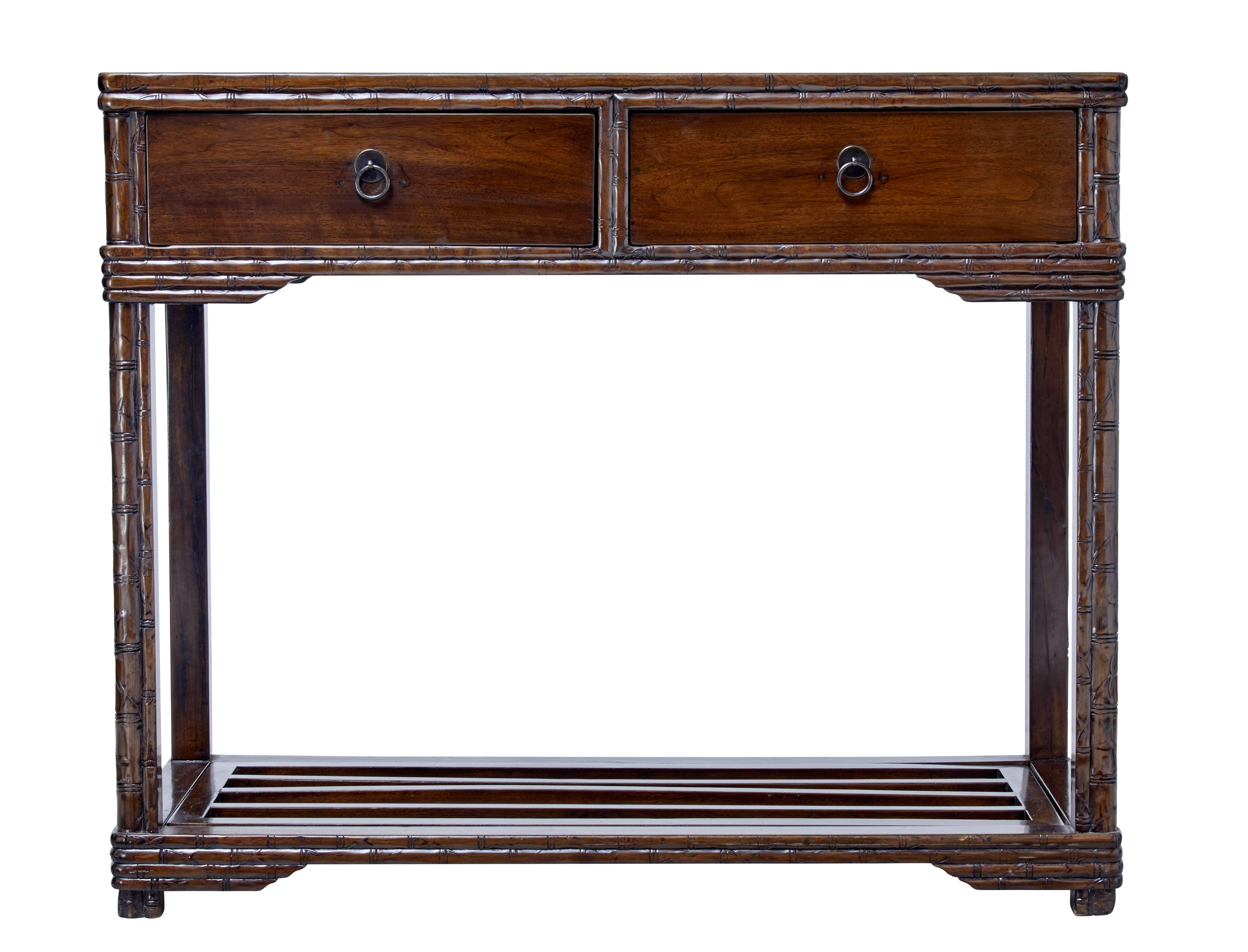 Good quality Chinese consul table, circa 1890.

Ideal for the hall way or as a side table. Carved faux bamboo to the top, drawer fronts and legs. Two deep drawers with later fitted ring handles.

Legs united by storage rack.

Lacquered finish,