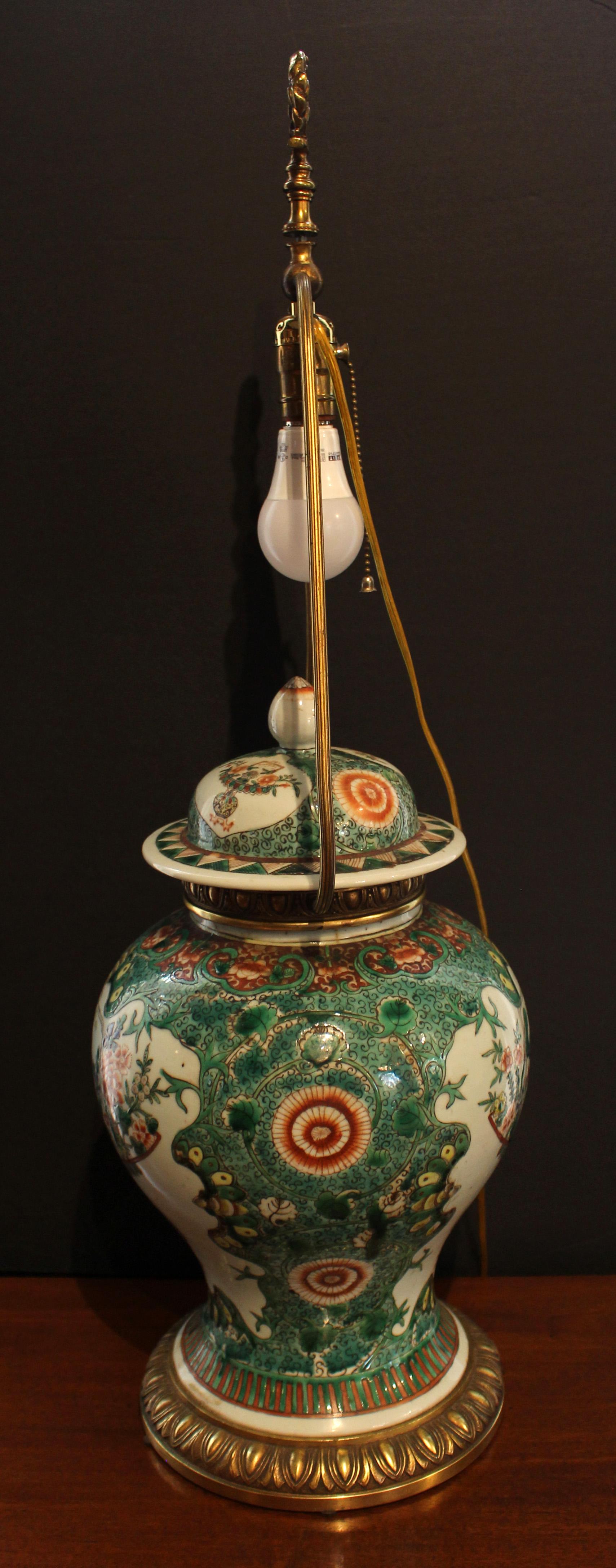 Late 19th century Chinese export famille verte temple jar, now mounted as a lamp. Baluster form with cover. Handsome bronze mounts. Qing dynasty. The bottom was shattered & mended but the entire body is unbroken. Finial reattached. The 1920s