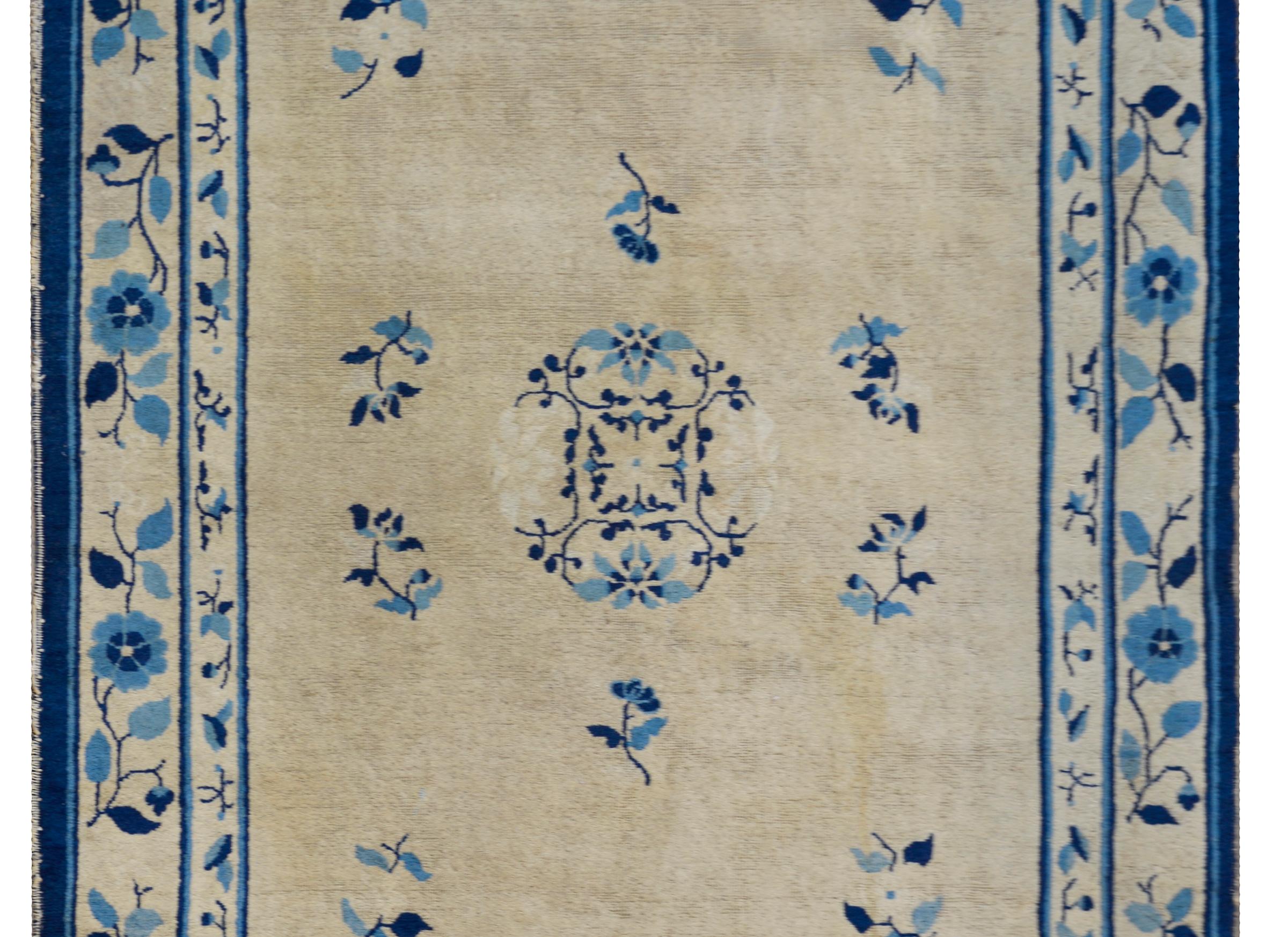 An outstanding late 19th century Chinese Peking rug woven in natural un-dyed wool with a large round chrystantmum medallion amidst a field of more chrysanthemums and peonies, all woven in light and dark indigo, and surrounded by a simple but