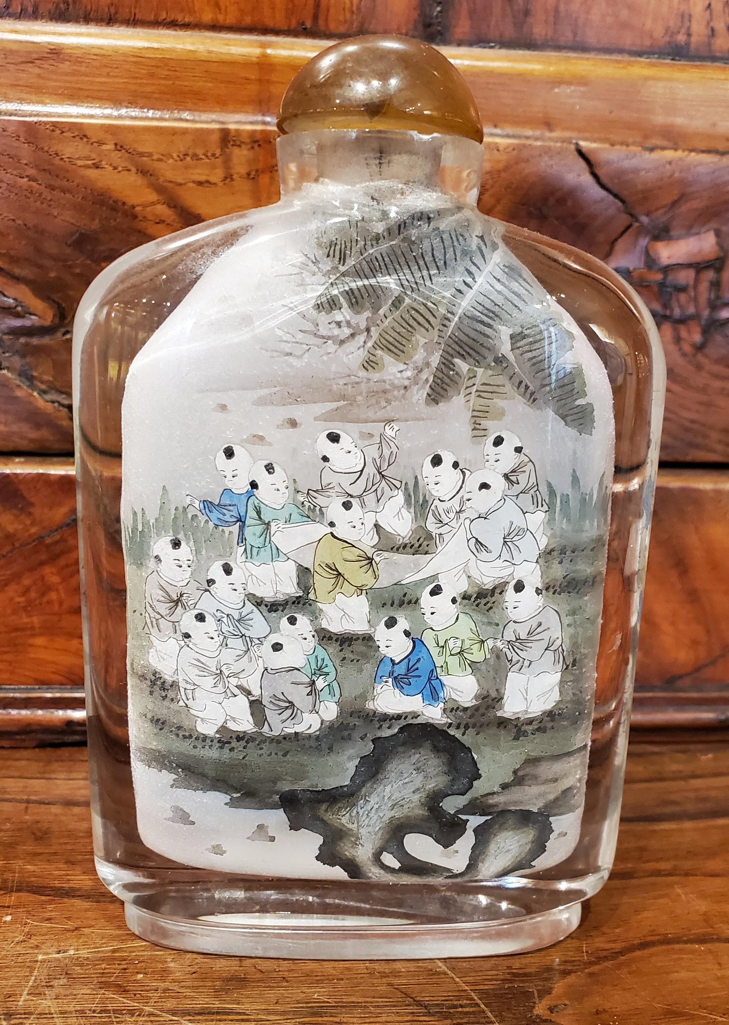 This beautiful late 19th century Chinese reverse painted glass snuff bottle is an incredible example of the intricate skill required for reverse painting with a detailed scene inside the front and back surfaces. This painting technique is known as