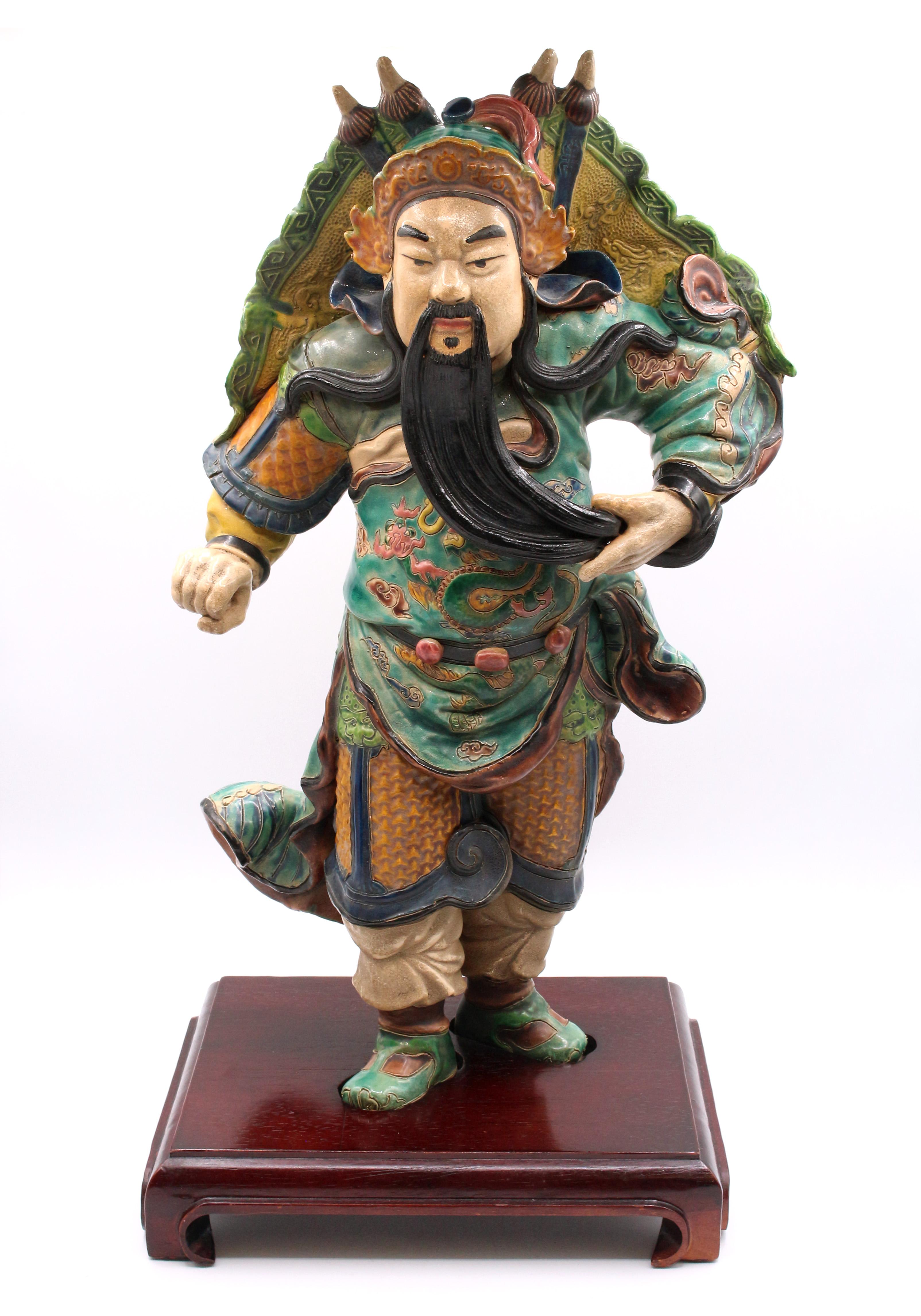 Late 19th century roof tile figure, Chinese. Polychrome glazed stoneware pottery. A man with long flowing beard and flowing robe decorated with dragons in a dramatic stance supported by a custom stand. Some normal wear & original back hole filled