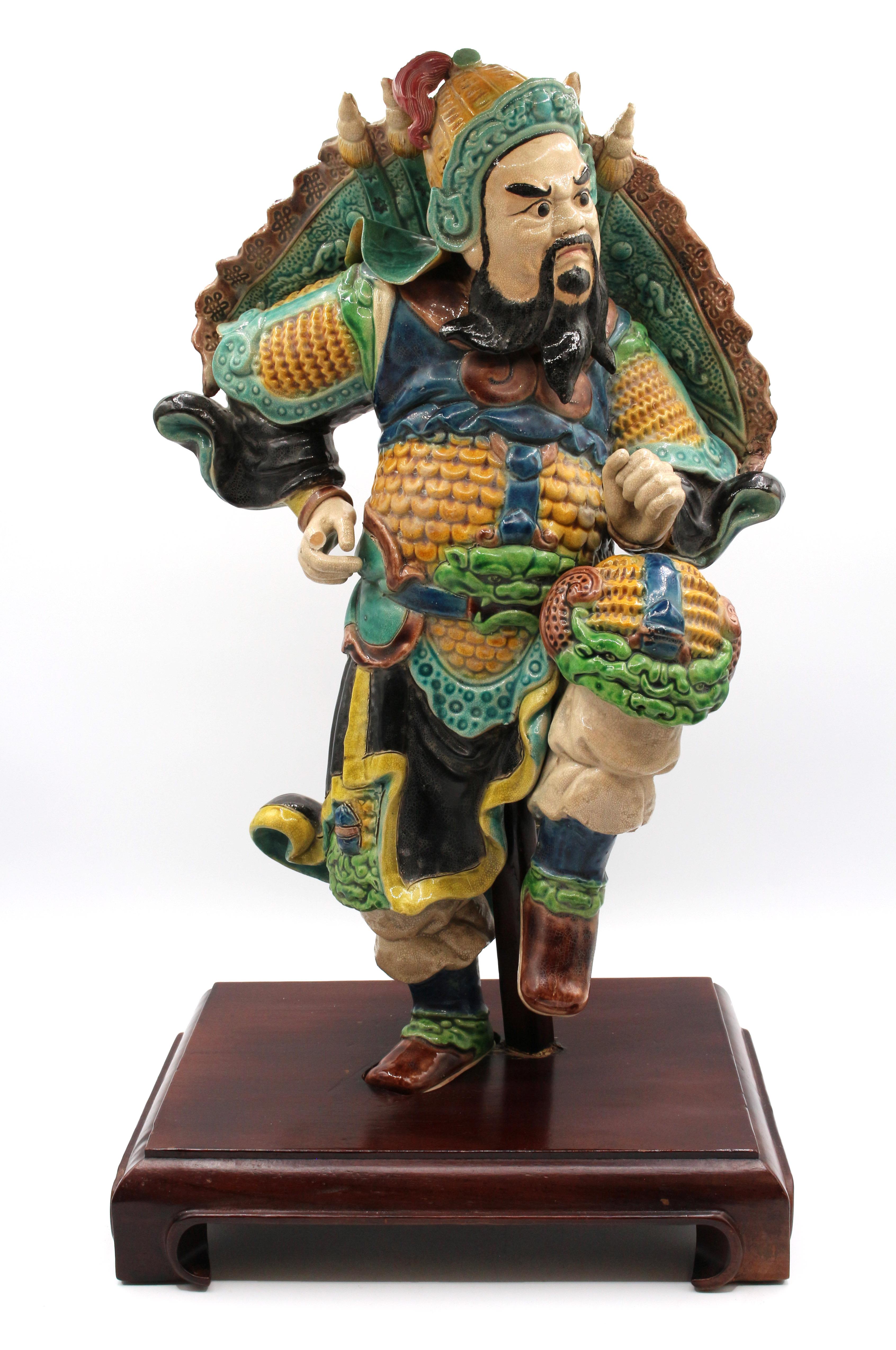 Late 19th century roof tile figure, Chinese. Polychrome glazed stoneware pottery. A man in dramatic pose, apparently in battle gear replete with foo dog head knee protectors. One finger missing, otherwise normal wear & degrading commensurate with