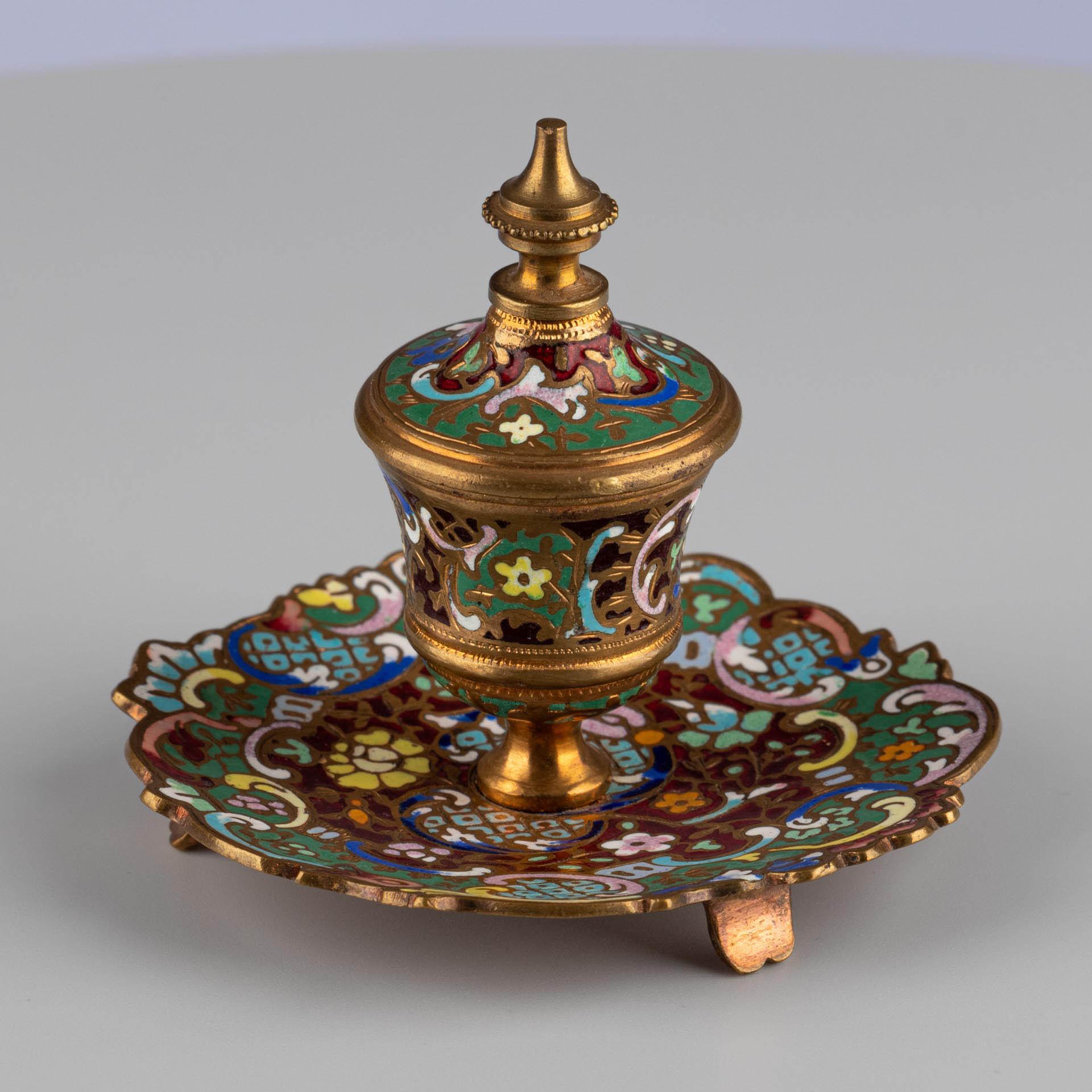 Tintenfass mit Cloisonné-Emaille

Herkunft: Frankreich
MATERIAL: Bronze mit polychromem Cloisonné-Email
Datum: CIRCA 1870-1890

Abmessungen:
H × B × T: 8 × 8 × 8 cm

Beschreibung:
Dieses kleine Tintenfass besticht durch seine dekorative Präsenz und