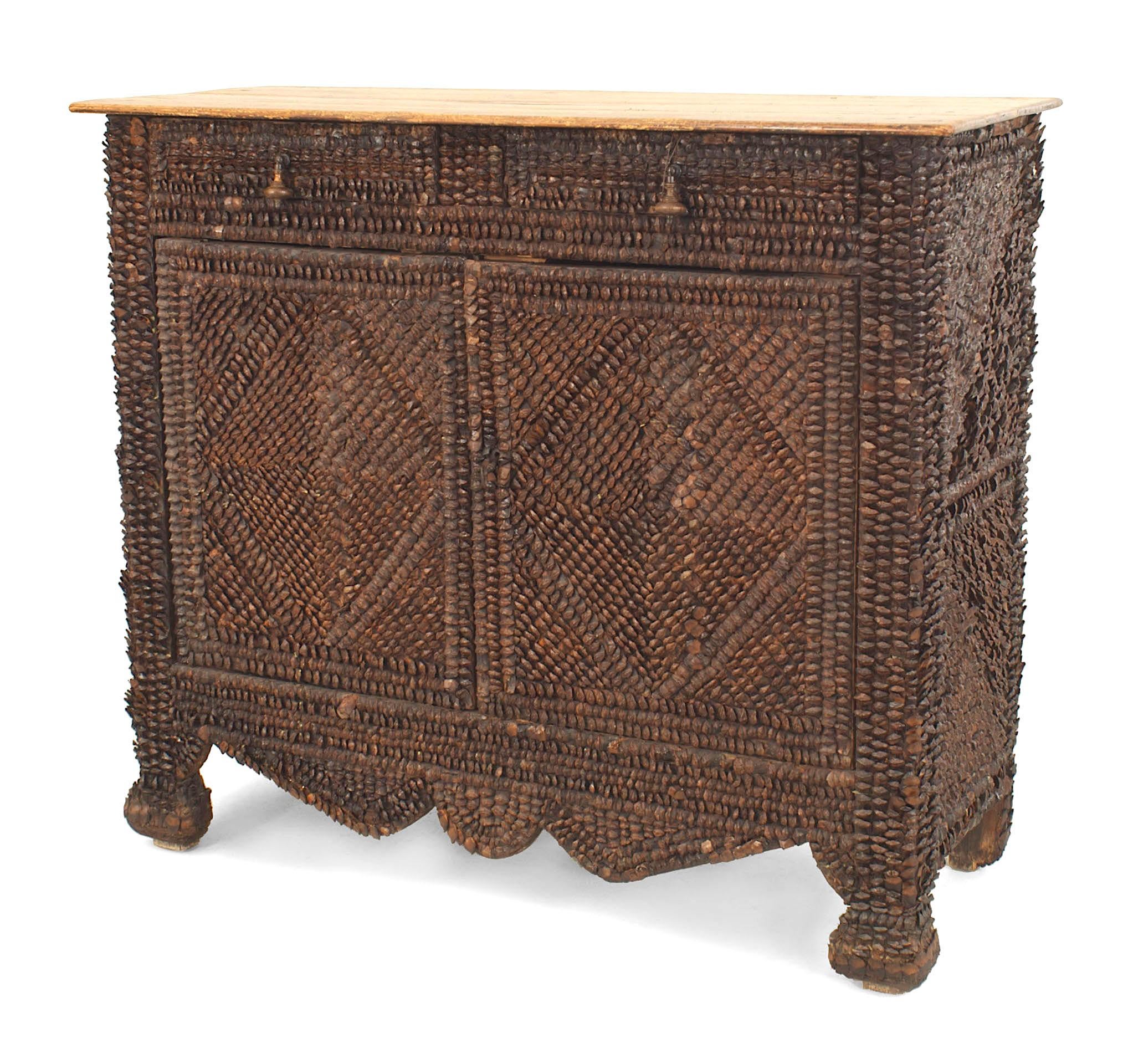 Rustic Continental (probably French late 19th Century) pine cone decorated veneer cabinet with 2 doors having a geometric pattern under 2 drawers with an antique pine top.
 