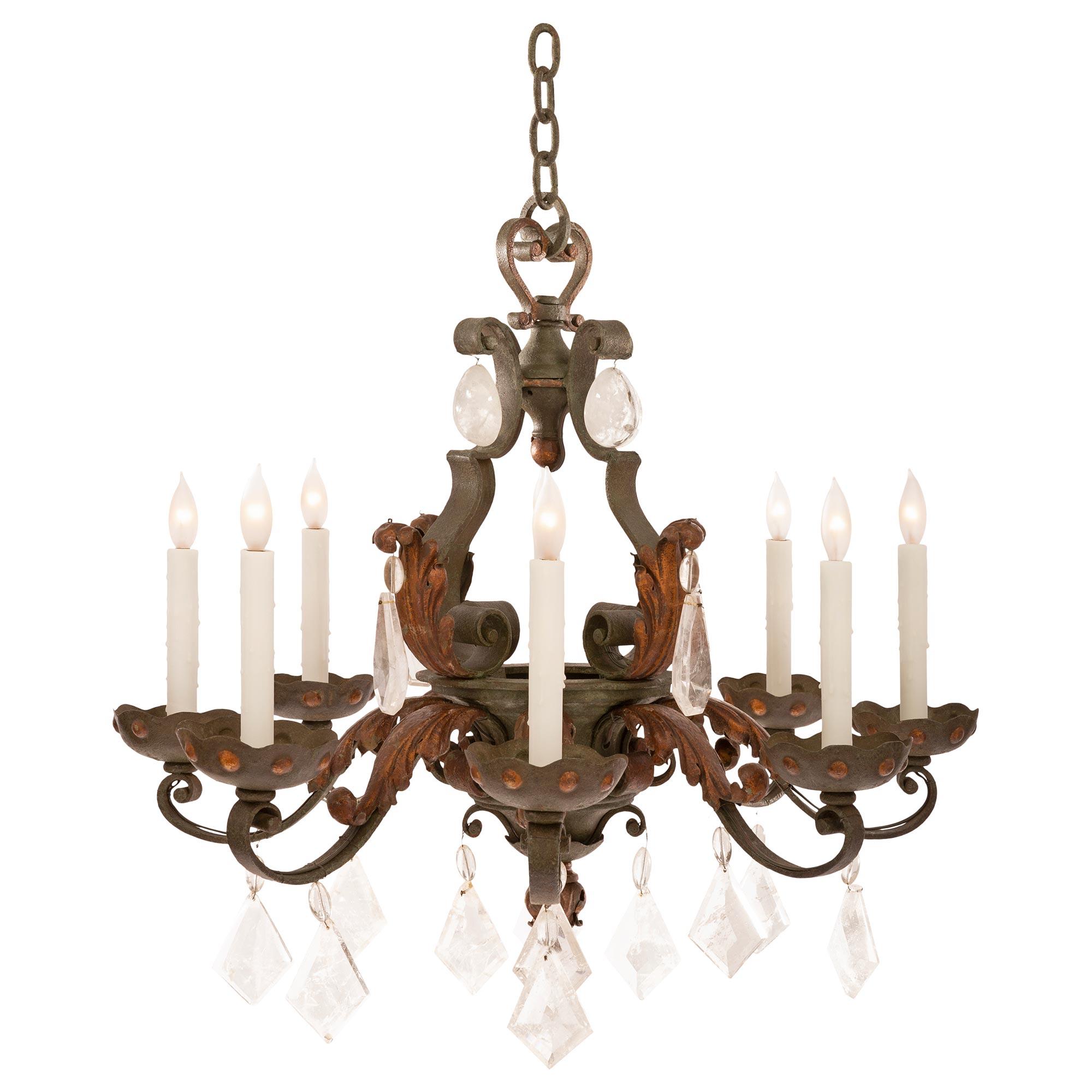 A beautiful Country French late 19th century Louis XV st. wrought iron and rock crystal chandelier. The eight arm chandelier is centered by a charming bottom foliate finial centered by a lovely array of most decorative kite shaped cut rock crystal