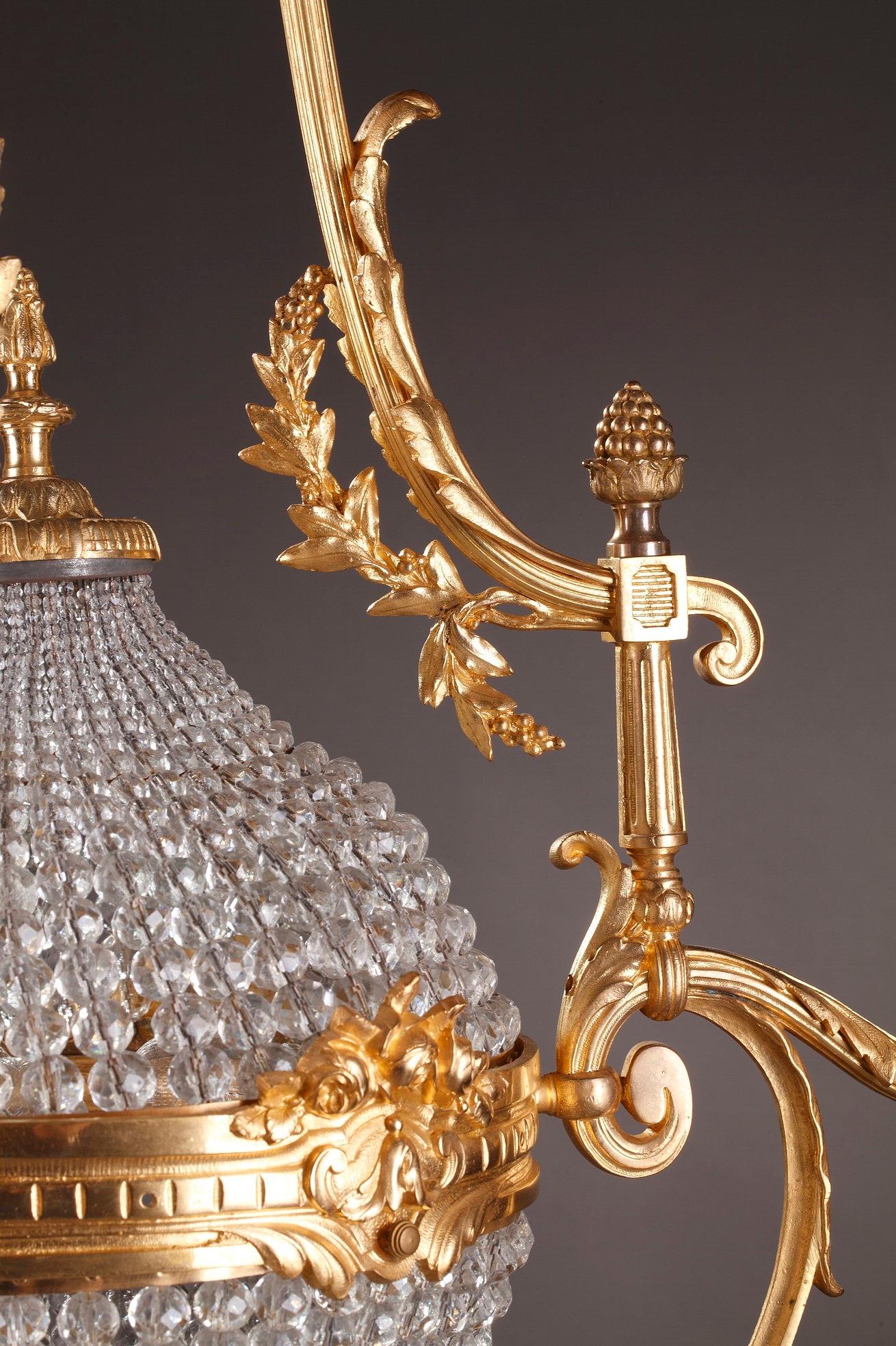 Monumental basket-shaped chandelier crafted of cut-crystal and bronze. Beautifully designed, luminous prisms, drop-hung drippans and crystal drops hang from curved branches of gilt bronze. This late 19th century fixure boasts exquisite decoration of