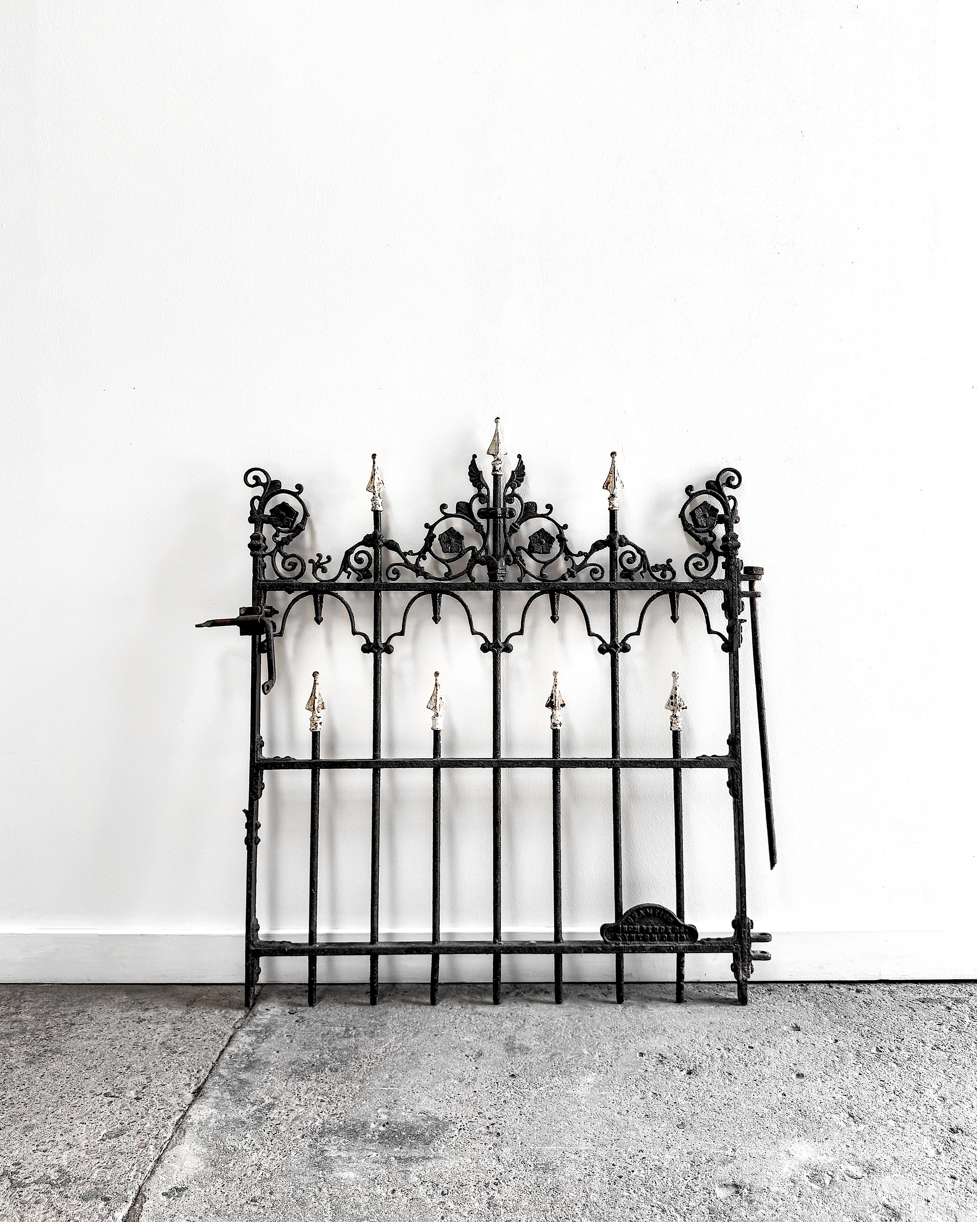 Wrought with ornate detail and storied provenance, this 19th-century cast iron garden gate was crafted by the Champion Iron Company of Kenton, Ohio—a foundry known for its decorative architectural ironwork during the Victorian era. Featuring pointed