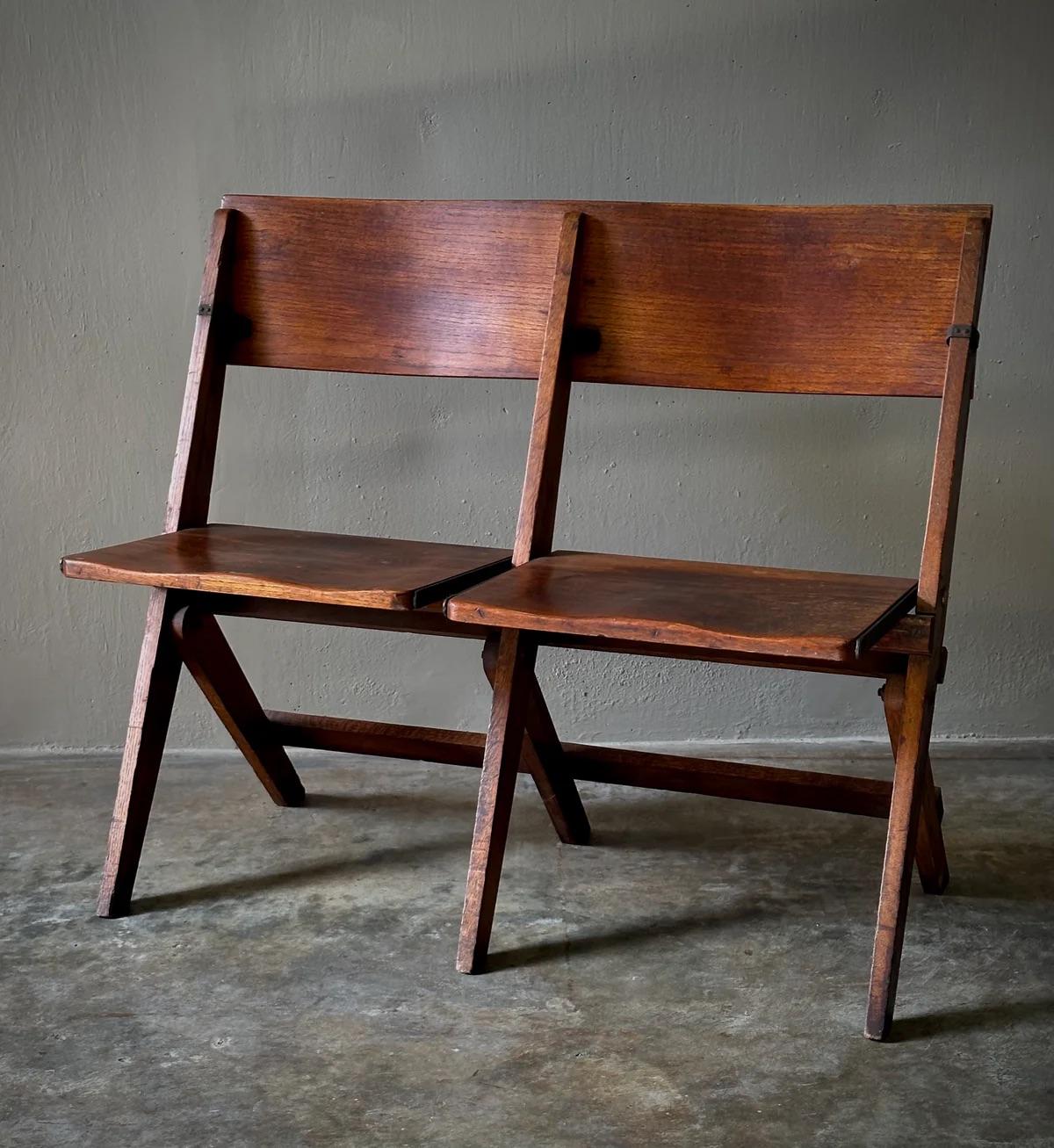 Esta silla plegable francesa de roble de doble asiento de finales del siglo XIX encarna una mezcla única de utilidad y comodidad. Su diseño presenta pequeños soportes estructurales metálicos que garantizan su durabilidad, mientras que los asientos y