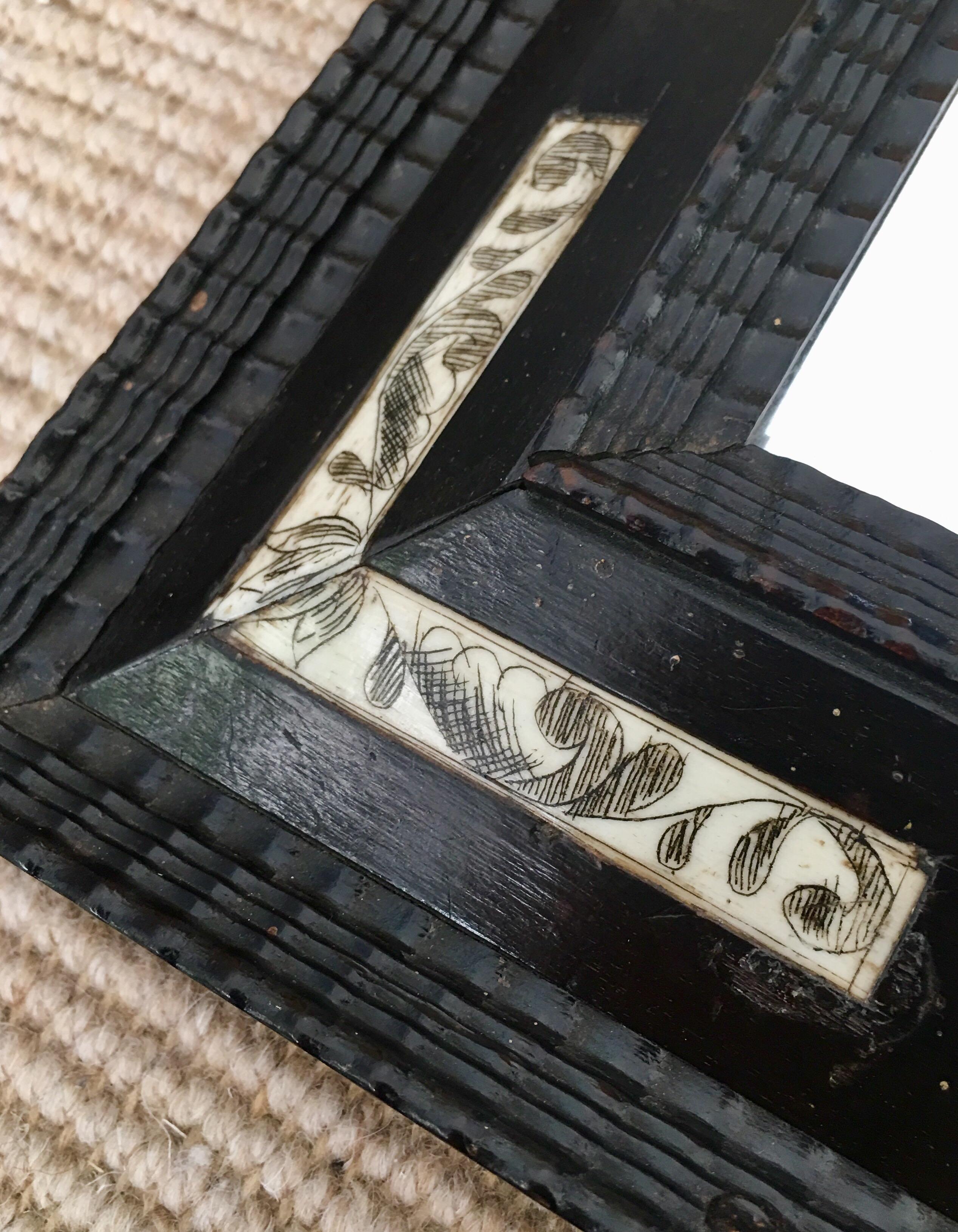 Ebonised Dutch style ripple frame mirror with amber style cabochons and bone scrimshaw corners. The plate is original.
