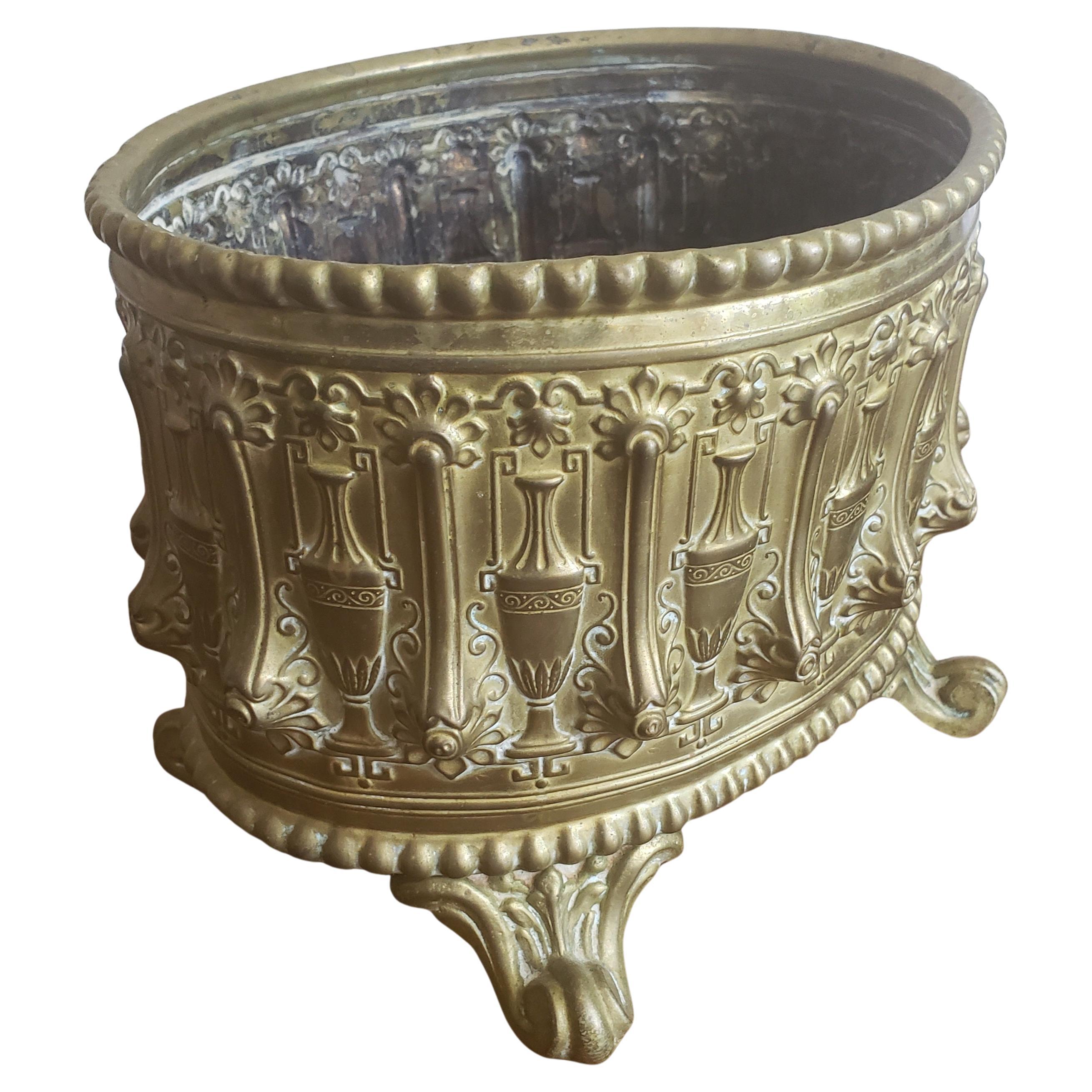 A late 19th century small embossed decorative oval brass jardiniere planter with 4 feet. Measures 9