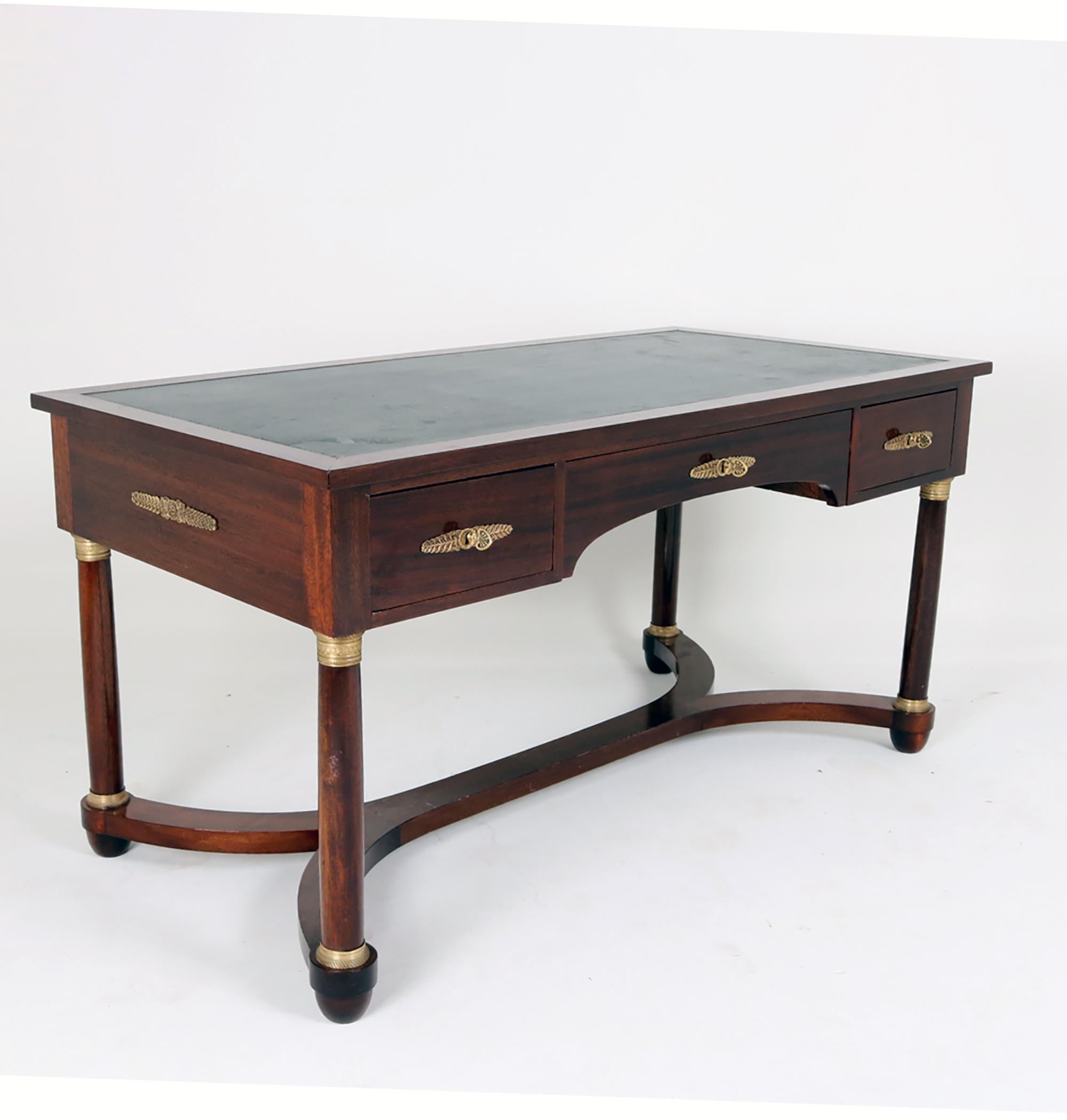 Empire-Schreibtisch mit Mahagoni-Furnier, verziert mit zahlreichen Messing-Applikationen. Die Oberfläche der Möbel ist mit einer Politur versehen, die einen dezenten Glanz verleiht. Die Tischplatte ist mit praktischem Leder bezogen.
Der Zustand
