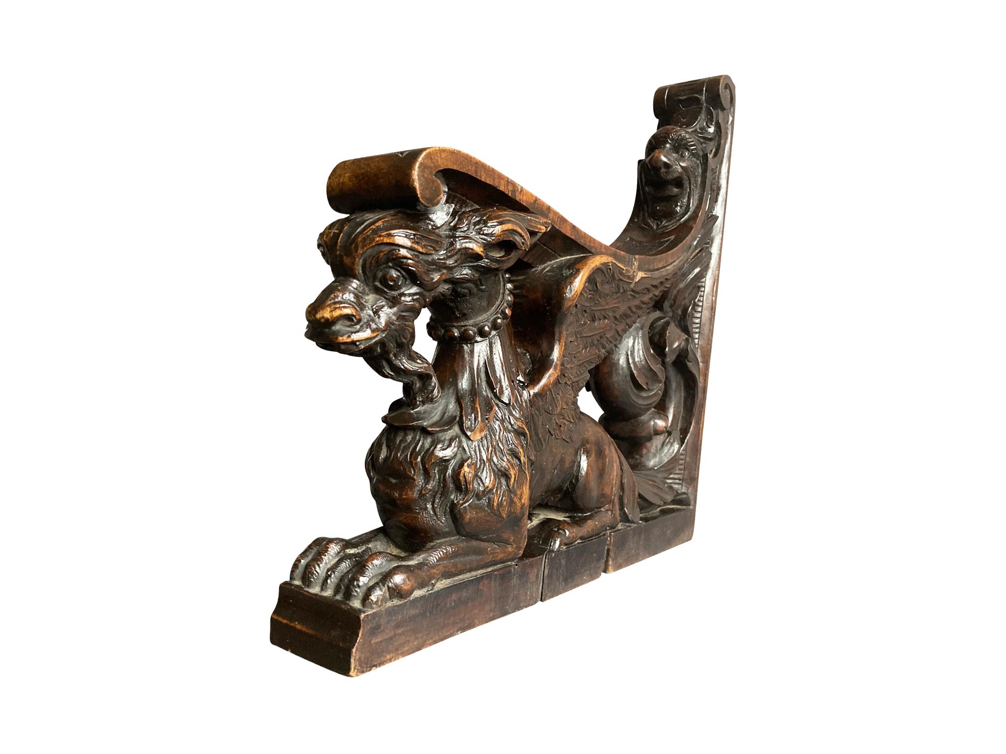 Late 19th century L-shaped architectural element, made in England. The charming design is a hand-carved griffon-shaped base that slopes upward and behind, transforming into an expressive face. The walnut wood has a warm red-brown patina. Over the