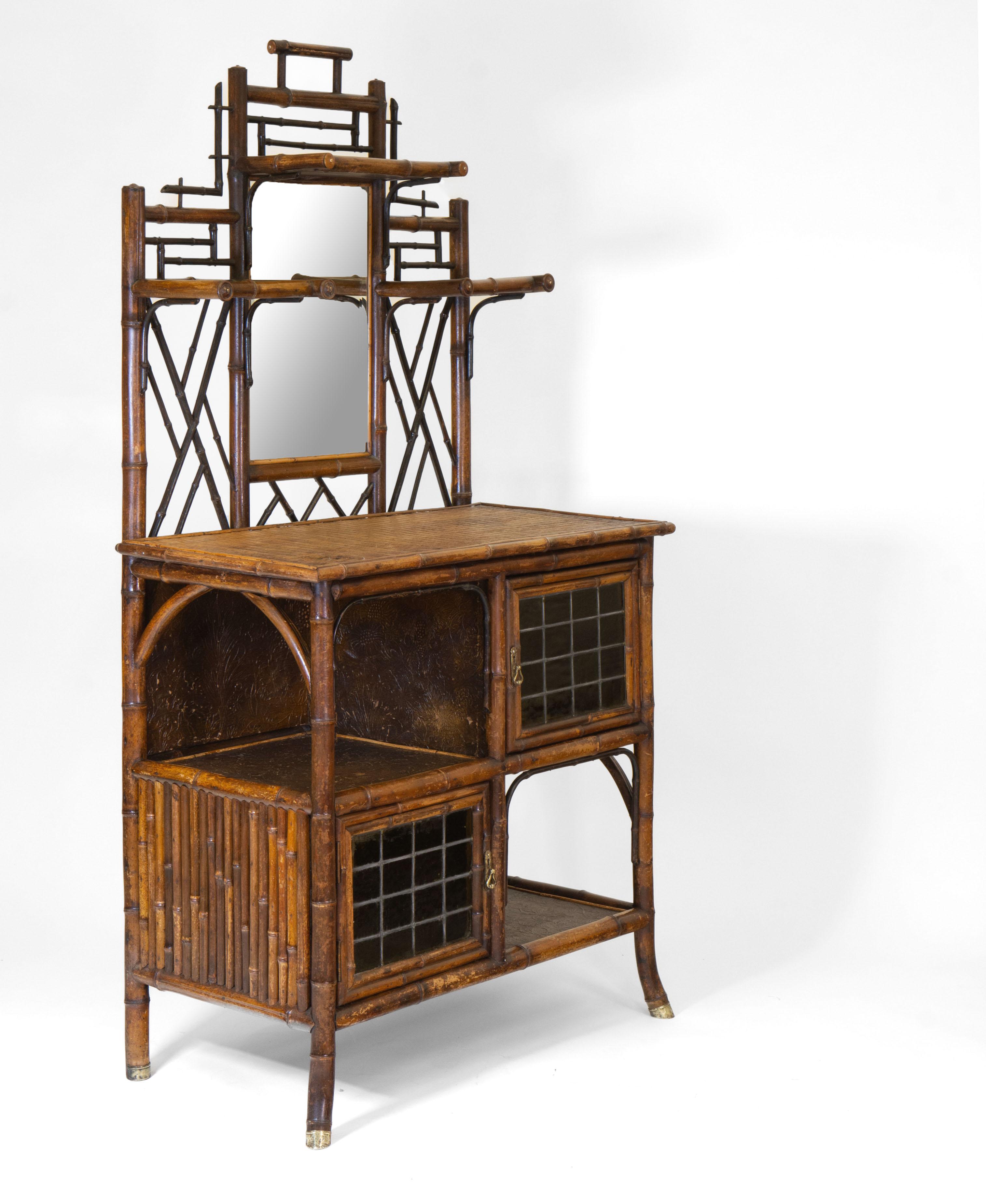 A wonderful late 19th century bamboo etagere/cabinet. Made by English firm W.F Needham. (1888-1901). Circa 1890.

The cabinet has 2 diagonally-set leaded, stained green glass doors, and two open compartments lined with embossed decorative paper.