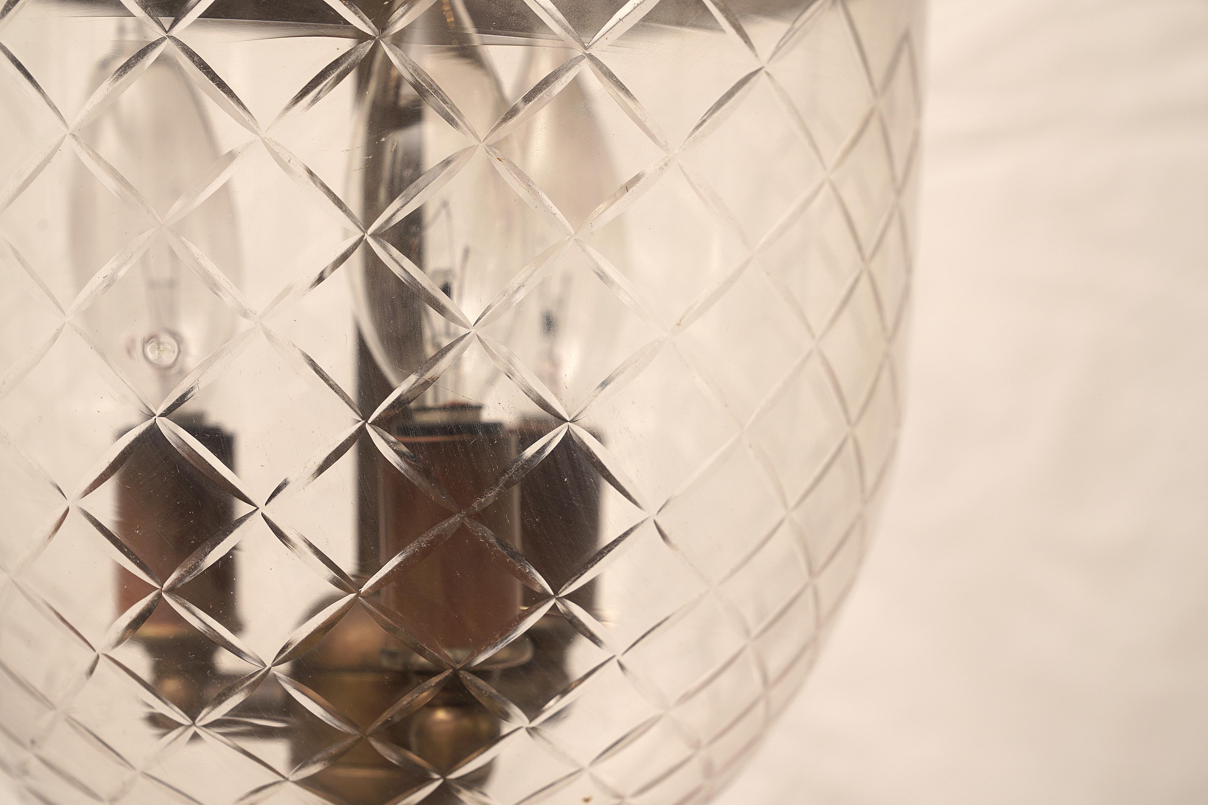 Handblown glass bell jar lantern with a prismatic diamond design etching, complete with the smoke bell lid. Originally used with candles, the lid kept the flame from scorching the ceiling. Embossed brass band with griffin hooks with natural patina