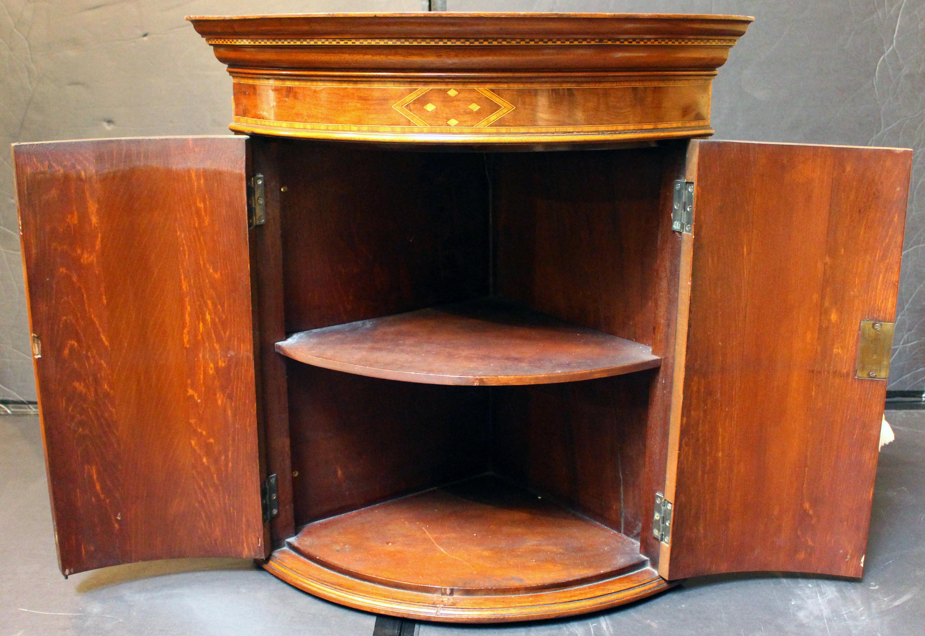 Meuble d'angle suspendu de la fin du 19e siècle, anglais. Renouveau du Sheraton. Acajou et placages d'acajou avec panneaux d'angle hautement figurés, incrustations de bois satiné et de bois exotique, incrustations de lignes, étoiles et garnitures de