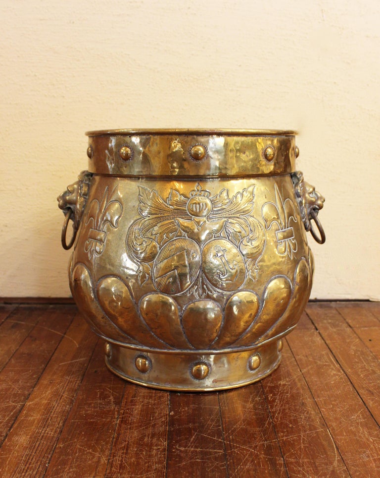 Brass coal hod or jardiniere - ideal as a wine/beer cooler, for kindling, as a jardiniere, etc. Lion mask & ring handles. Accent bosses at the top & base. Repousse work of gadrooning, fleur de lys, flower vase & coat of armor with shields crest.