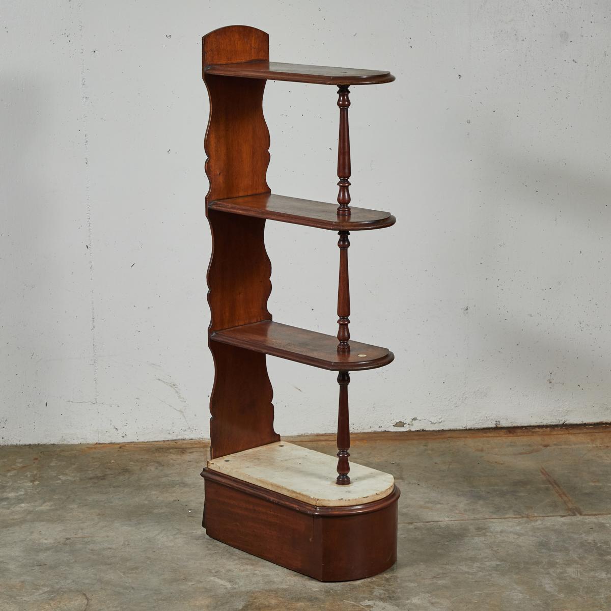 Late 19th-century English mahogany chemist's shelf. The elliptical shelves are connected on either side by a thin turned column and flat beveled support. The base is finished with an ivory-colored marble top, and conceals a secret back