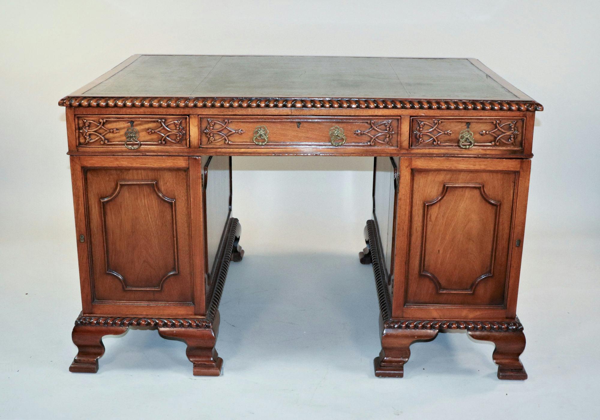 This exquisite partner's desk is a fine example of Chippendale-style furniture, characterized by its intricate and ornate design. The desk features gadroon carving along the edges, adding a touch of elegance and sophistication. On both sides, the