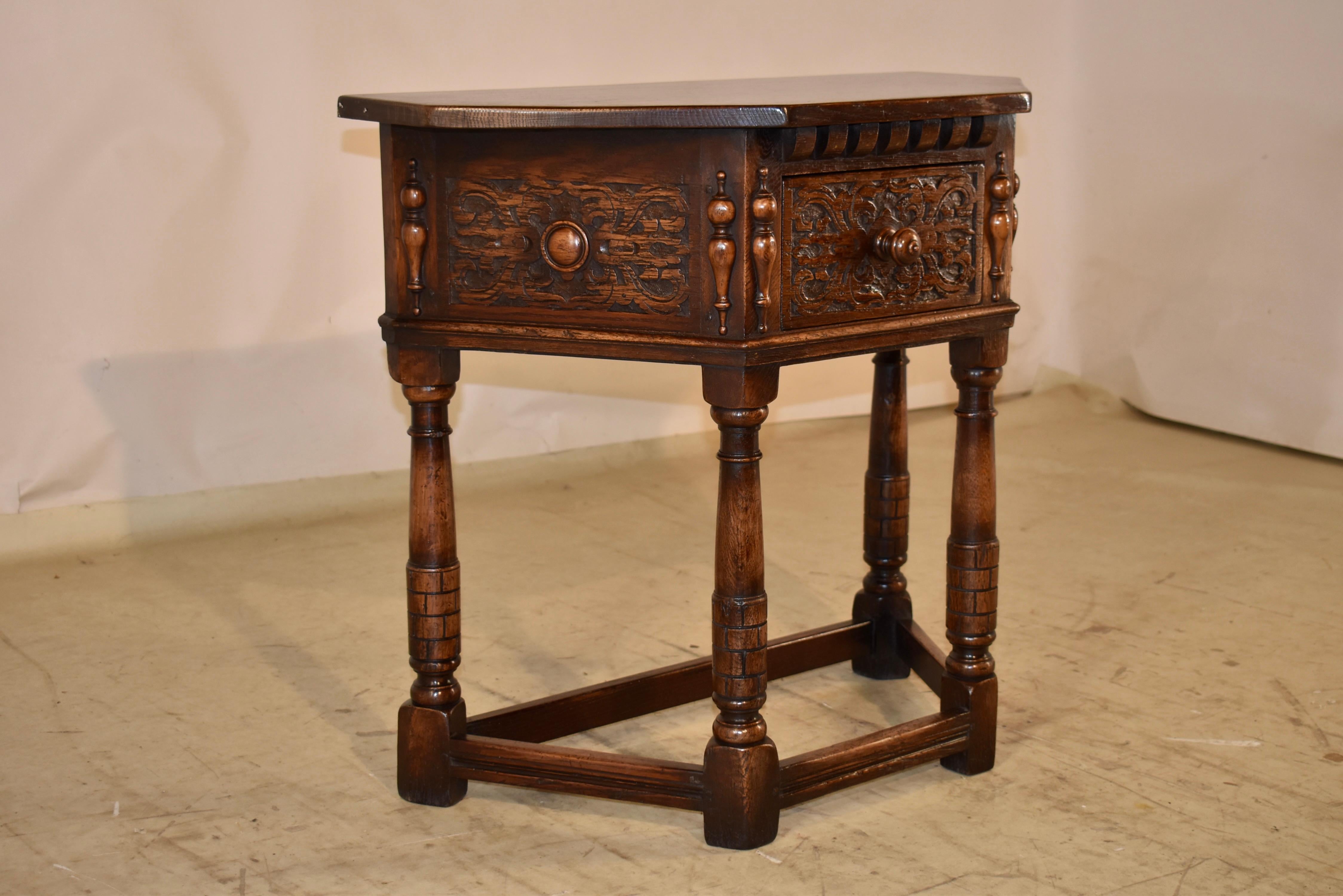 Late 19th Century Oak console table from England.  The top is nicely angled and follows down to wonderfully hand carved side panels and front drawer. The side panels and drawer are flanked by applied half turnings, for added dimension and design