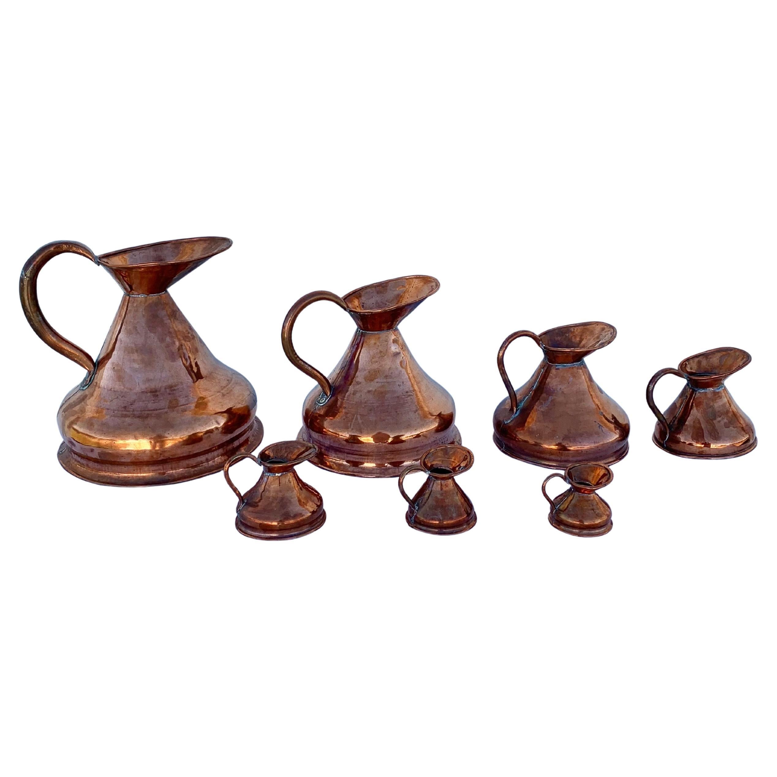 Questo set di sette brocche da pagliaio della fine del XIX secolo è stato realizzato a mano in rame alla fine del 1800. Questa serie unica di brocche, spesso chiamata brocca da pagliaio, veniva utilizzata per misurare con precisione il sidro e la