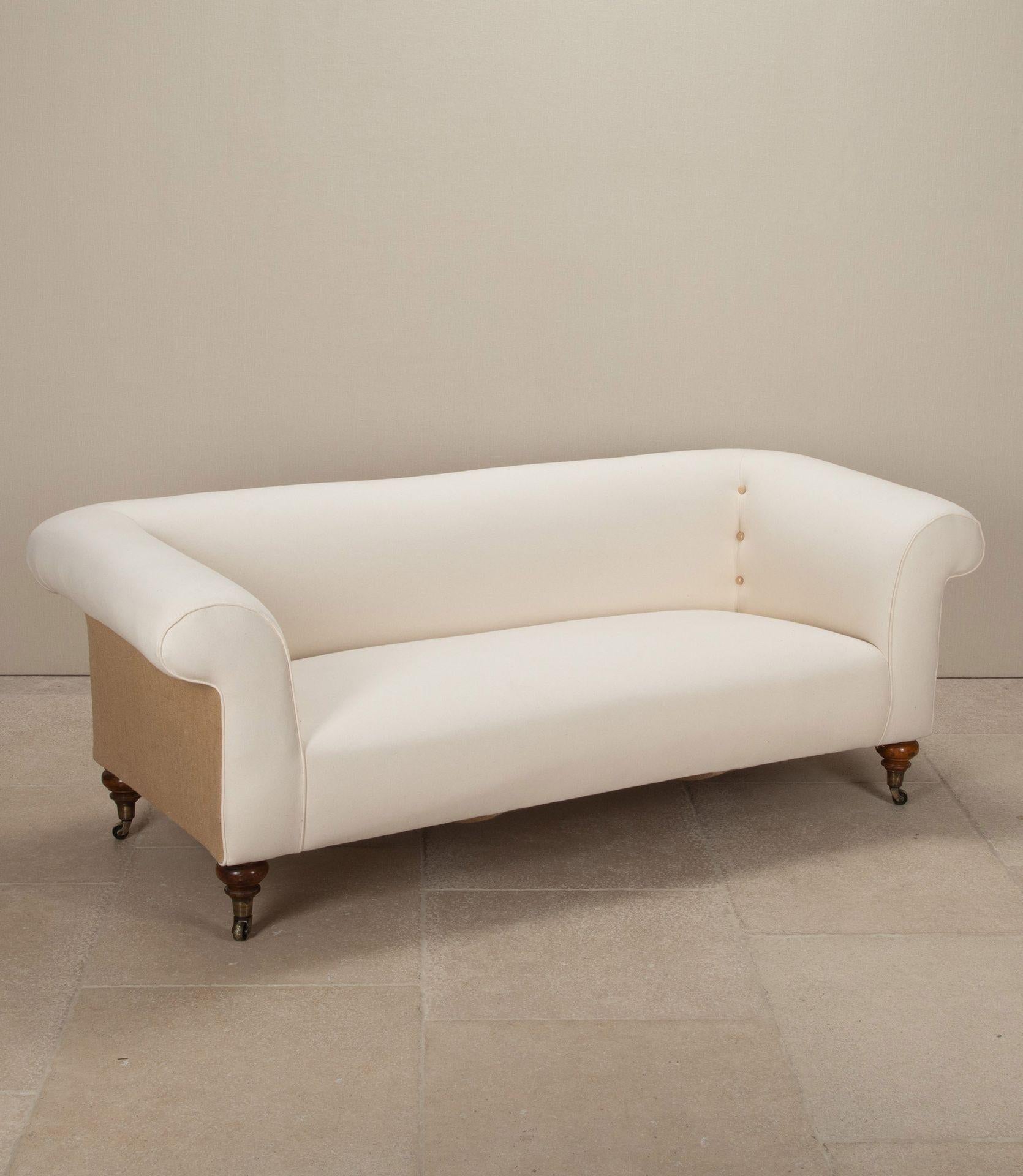 Divano Chesterfield di una casa di campagna inglese della fine del XIX secolo.
Rivestito in calico naturale e iuta. Termina con gambe in noce e rotelle in ottone.