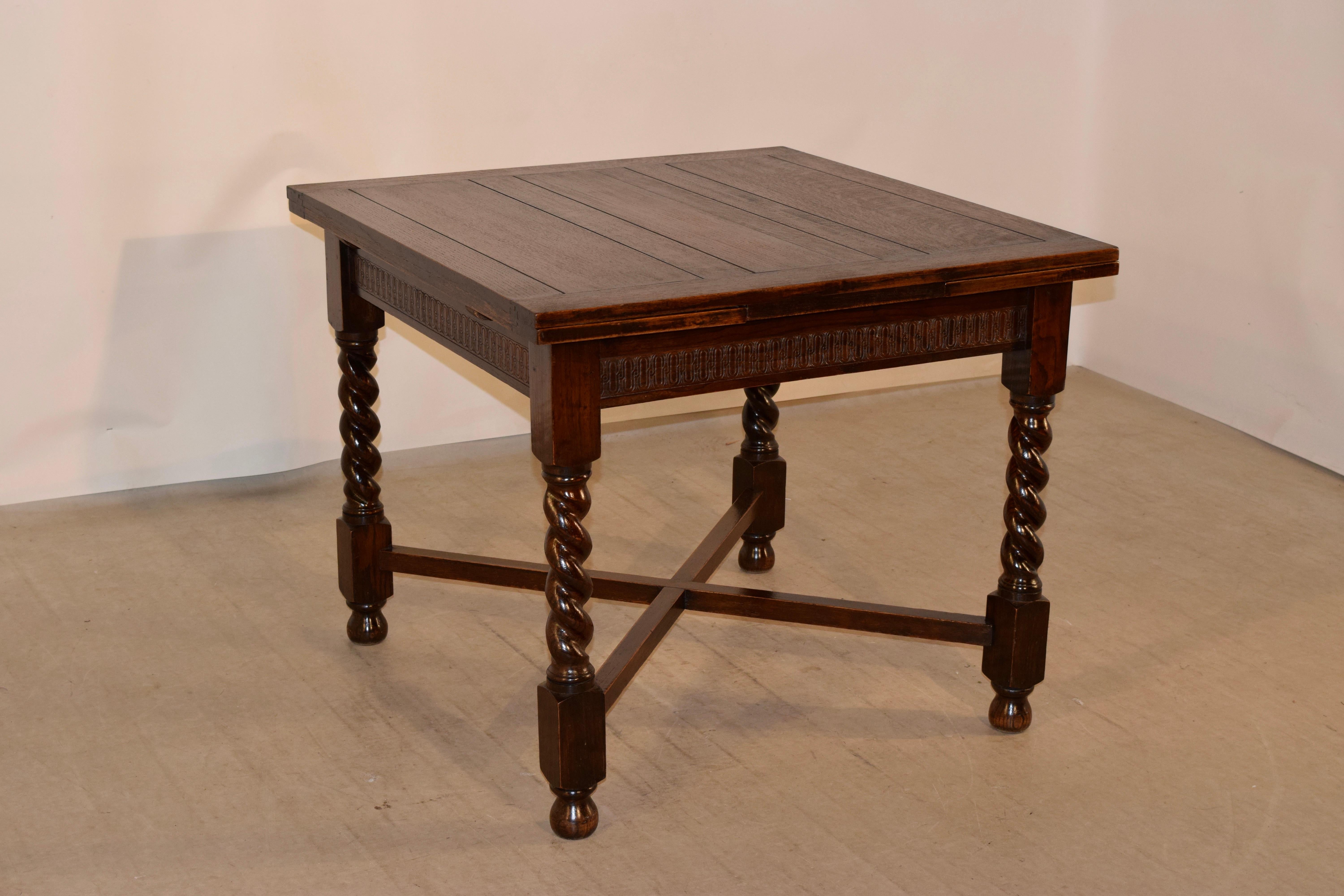 Late 19th century oak draw leaf table from England with a paneled top and leaves, following down to a hand carved decorated apron and supported on hand turned barley twist legs joined by cross stretchers and raised on bun feet. The apron measures 24
