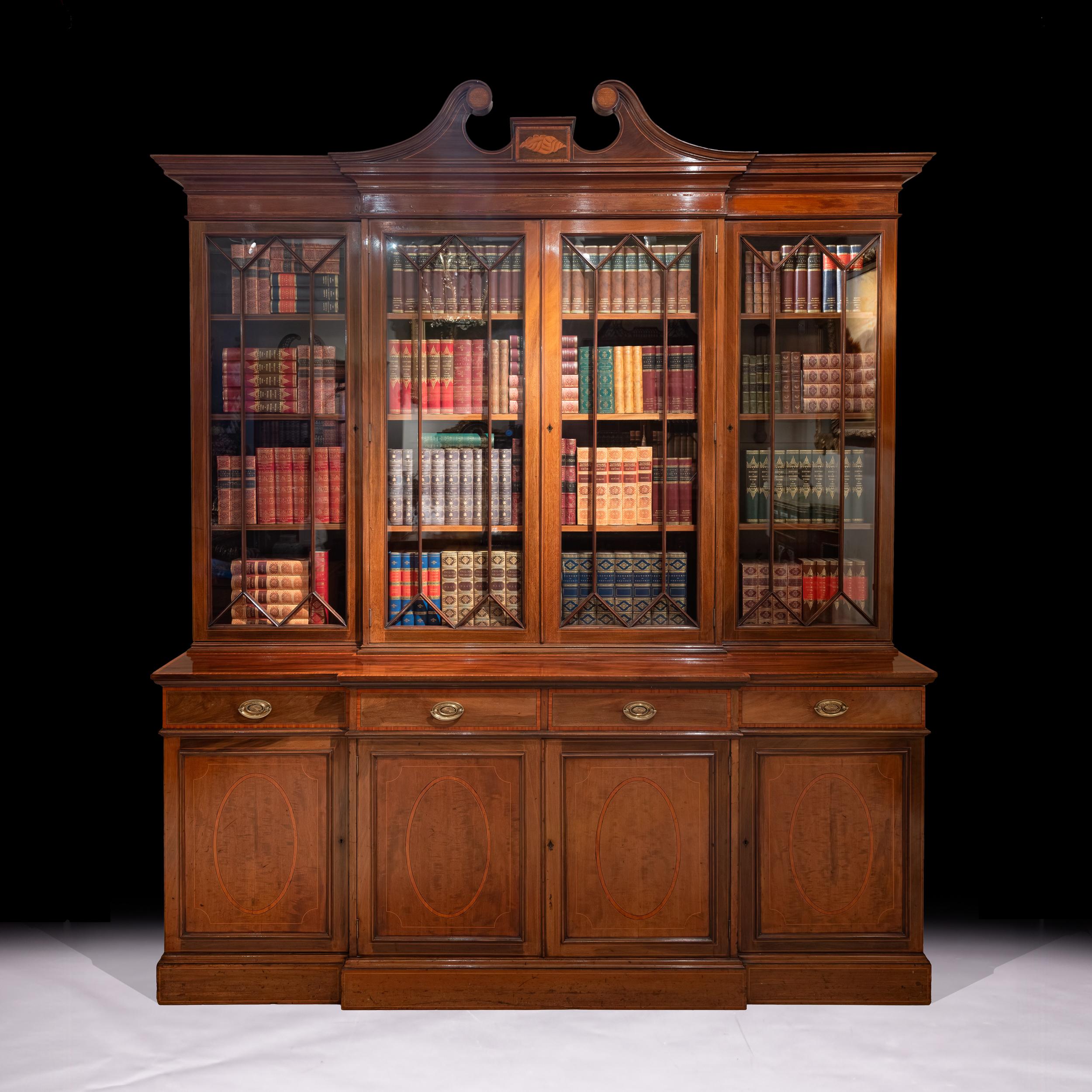 Libreria a quattro ante a ribalta di Maple & Co. della fine del XIX secolo, con la parte superiore con cornice frontale a collo di cigno che sovrasta quattro ante geometriche vetrate, l'interno a ripiani su quattro cassetti e quattro ante di