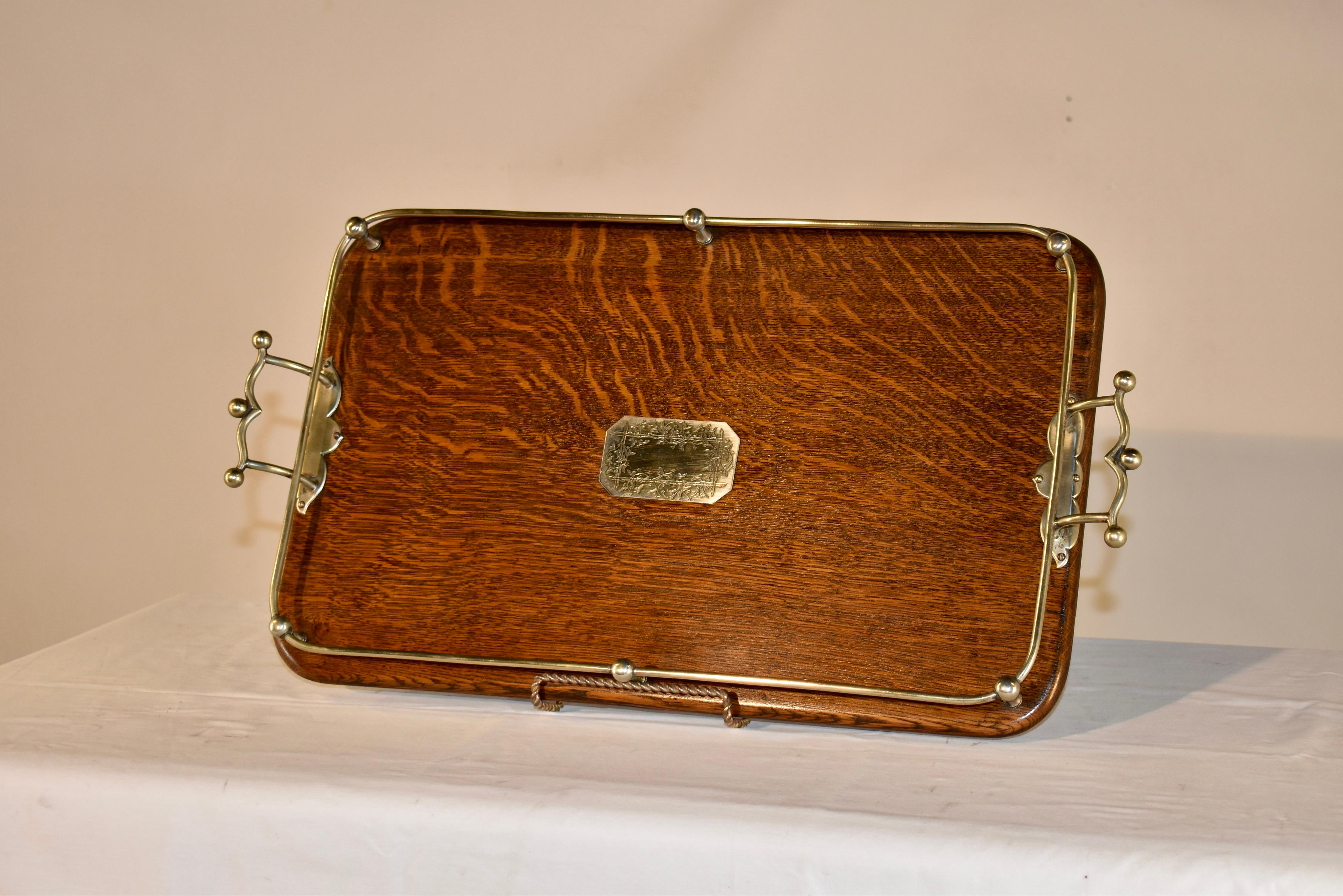 Late 19th century oak tray from England.  The tray has lovely graining along with a central silver plated plaque, which has a trellis and vine decoration.  The tray has a silver plated gallery and lovely cast handles, along with silver plated feet. 