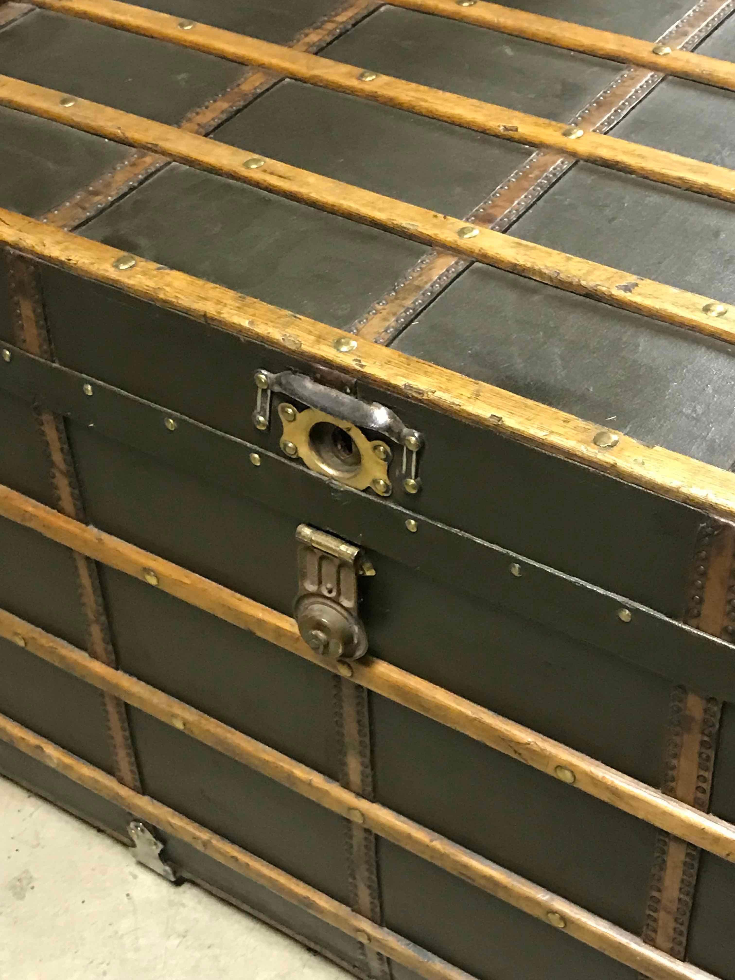 Late 19th-century English trunk or coffee table with wood detailing, metal hardware, and black leather. With green undertones. The piece has a remarkable aged patina and a handsome, sturdy appeal. This could still be used as travel storage, or as a