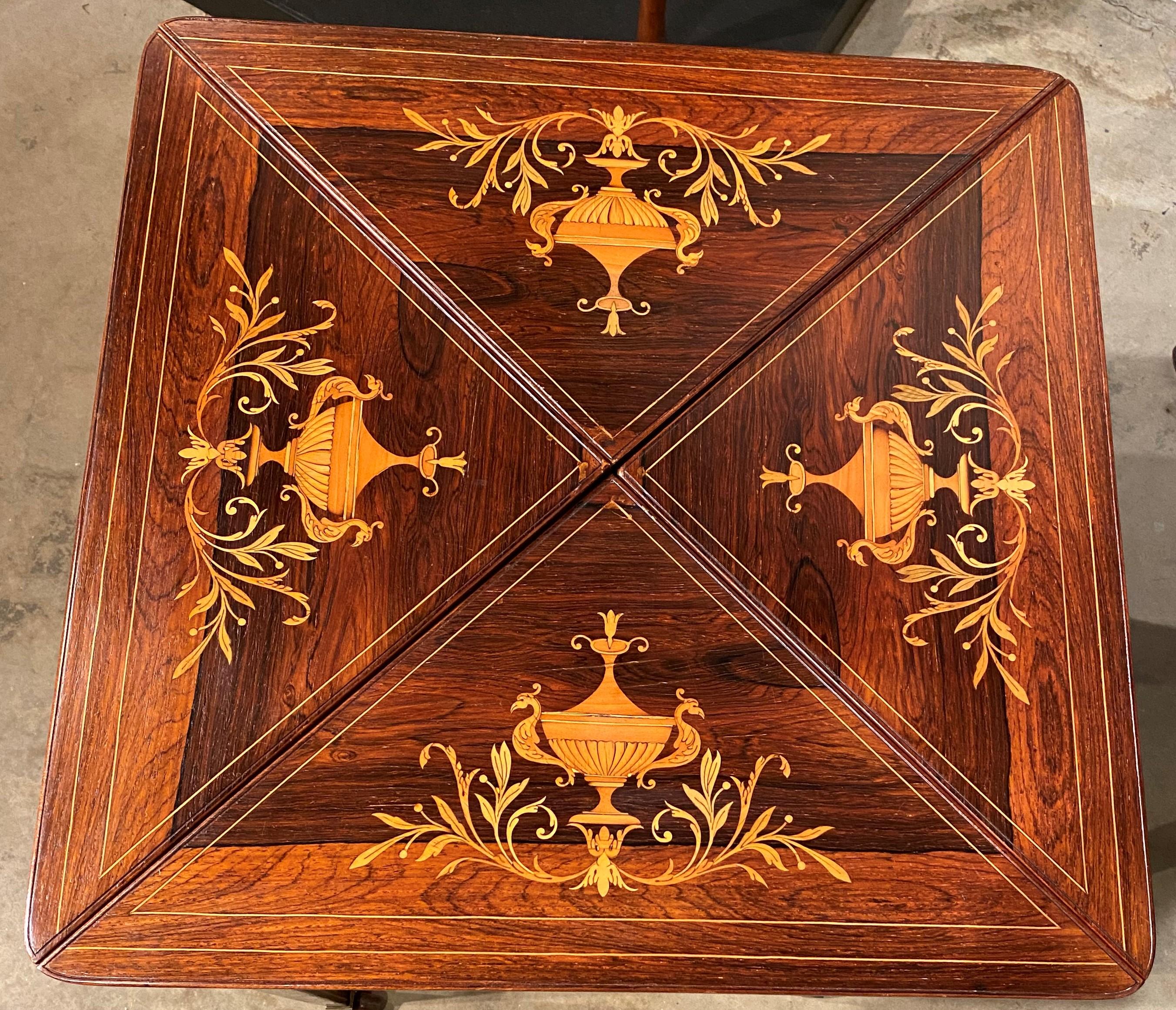 A wonderful example of an English handkerchief gaming table with exceptional satinwood scrolled inlay on each of the top four panels. Once the top is rotated 45 degrees, each top triangle panel can be folded open to reveal a green felt-lined gaming