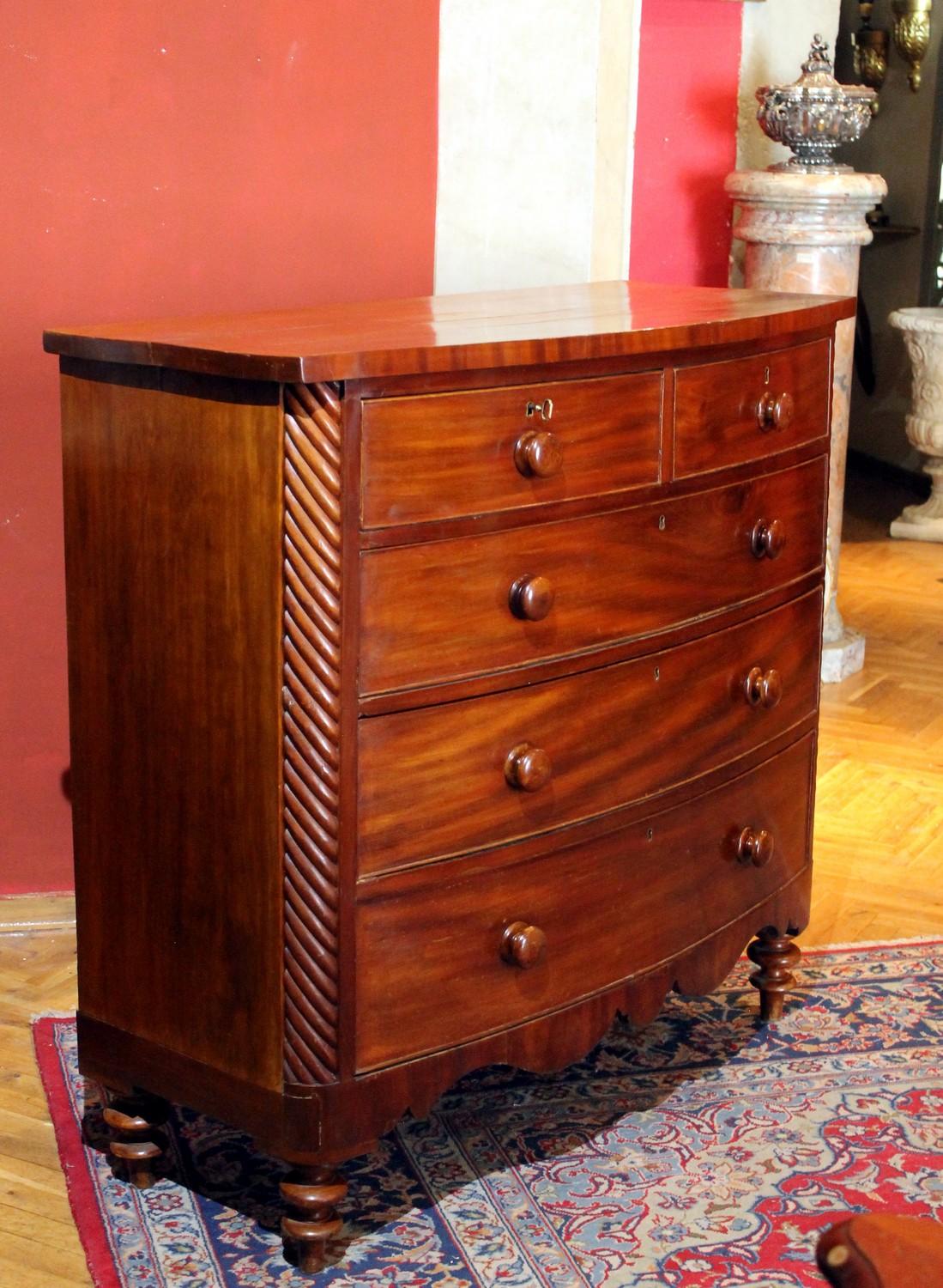 This late 19th-0early 20th century English handsome large and tall chest of drawers in rich mahogany has a bow front, is outfitted with five total drawers, two smaller top drawers, with three larger drawers below that are graduated in size. All