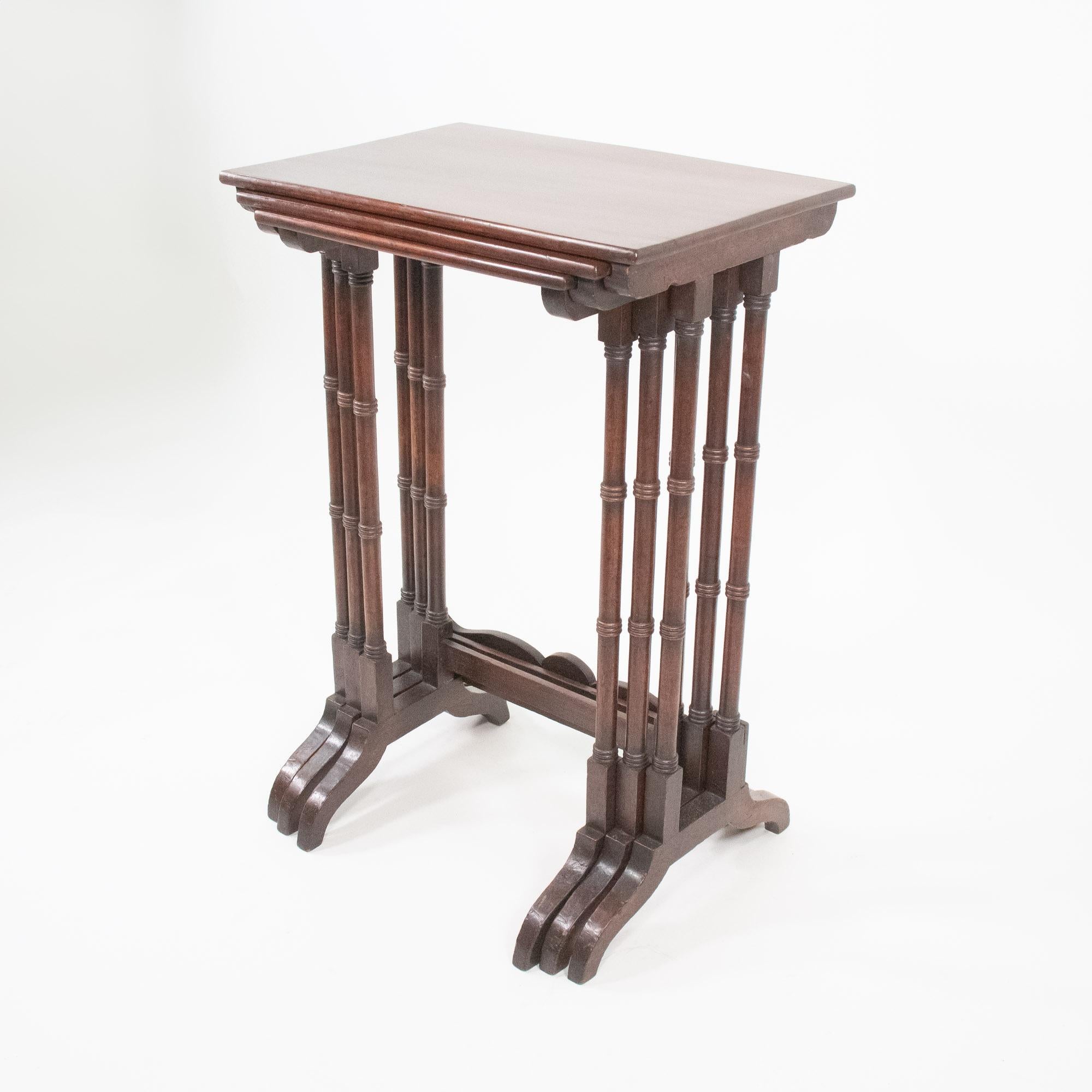 This late 19th-century English nest of tables set consists of three elegantly crafted tables in graduating sizes, designed to nest gracefully within one another without the legs touching. Made from luxurious mahogany, a highly favored wood during