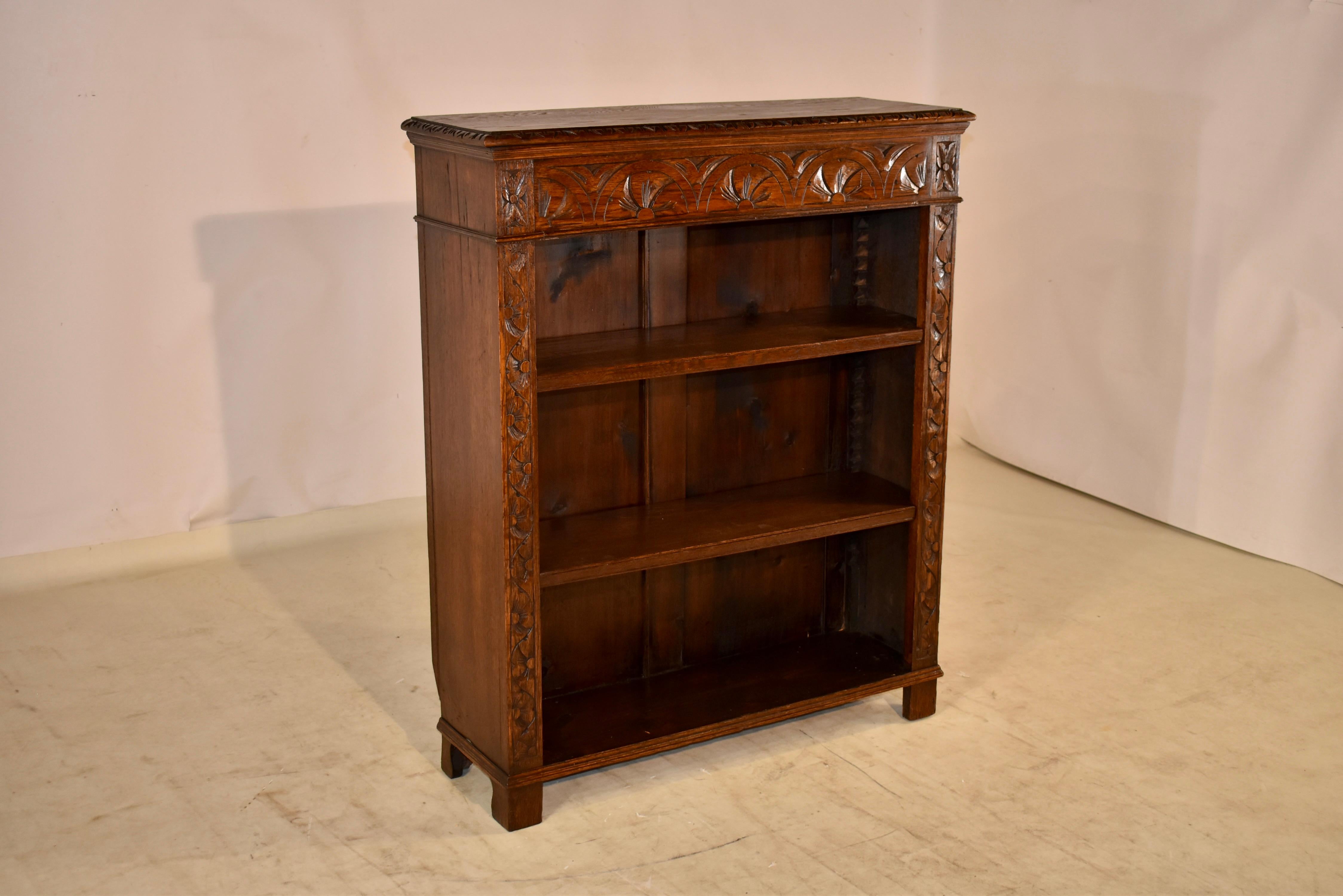 19th century hand carved oak bookcase from England. The top has a beveled and carved decorated edge following down to simple sides with molded detail, and a hand carved decorated case in the front. It has three shelves, two of which are adjustable.