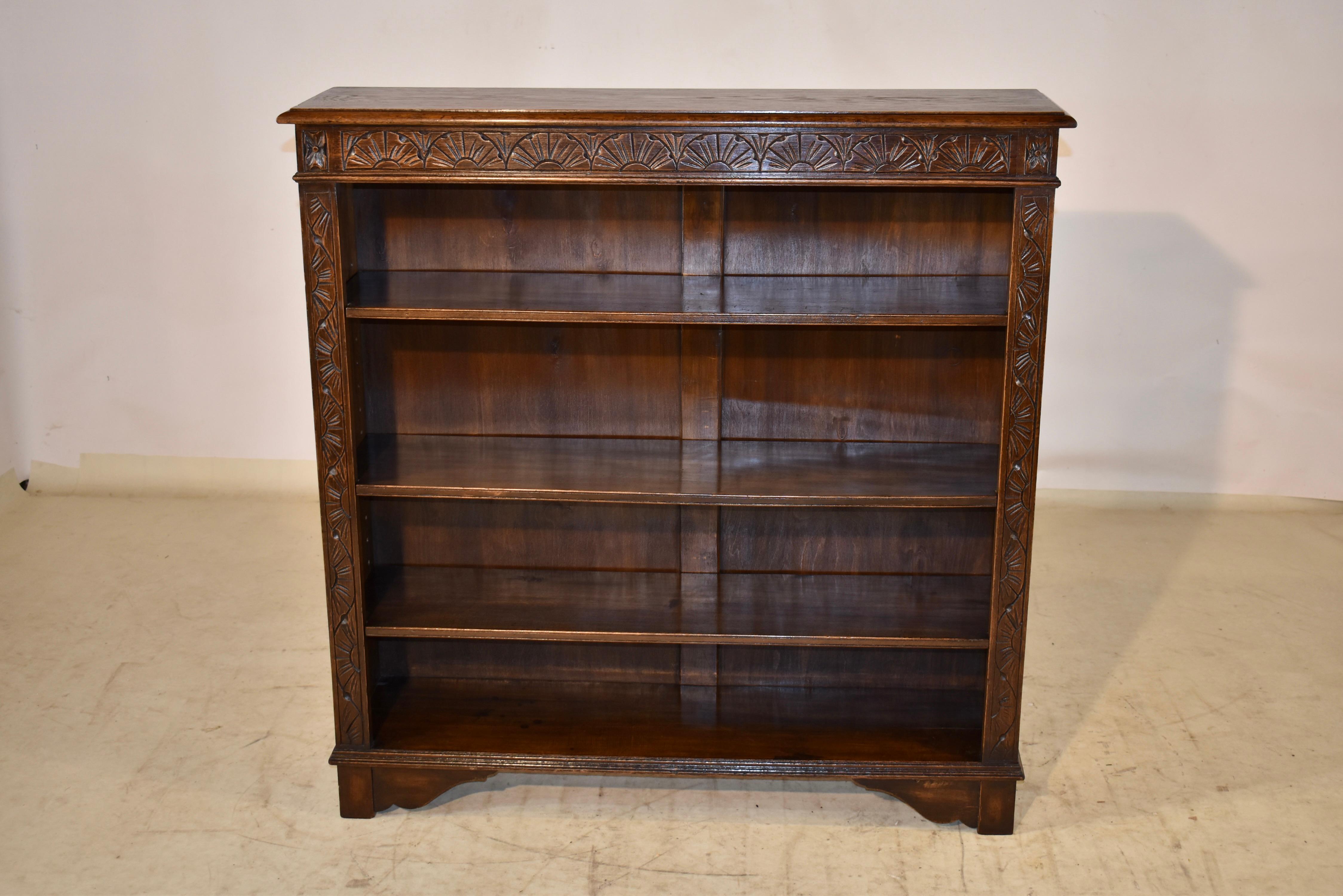Late 19th century oak bookcase from England. the top has a beveled edge and follows down to simple sides and a carved case on the front, for added design interest. The bookcase has three moveable shelves, and the bottom shelf is stationary. The case