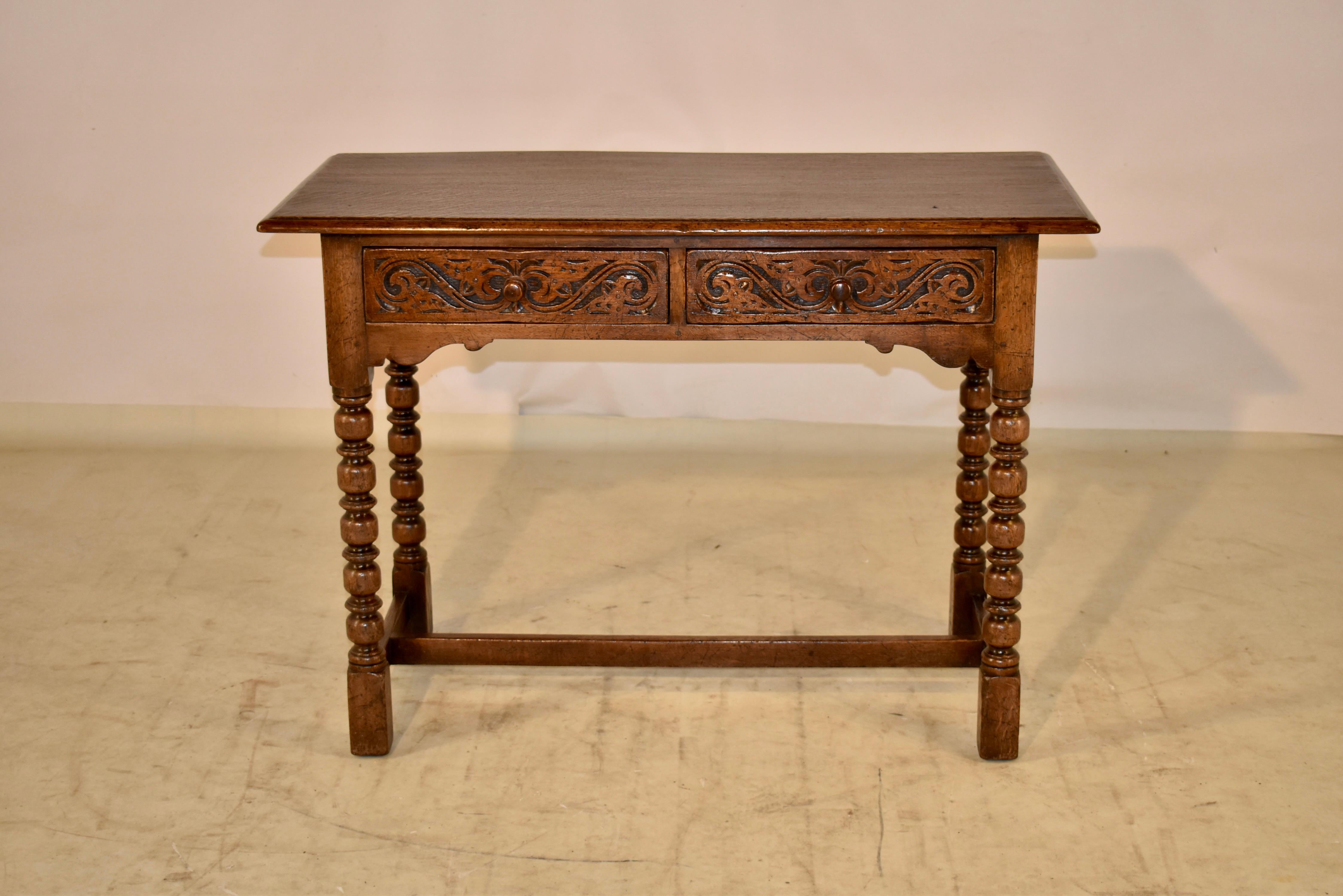 Late 19th century oak console table from England with a beveled edge around the two board top, over simple sides and two drawers in the front, featuring hand carved decorated drawer fronts. The apron in the front is scalloped for added design