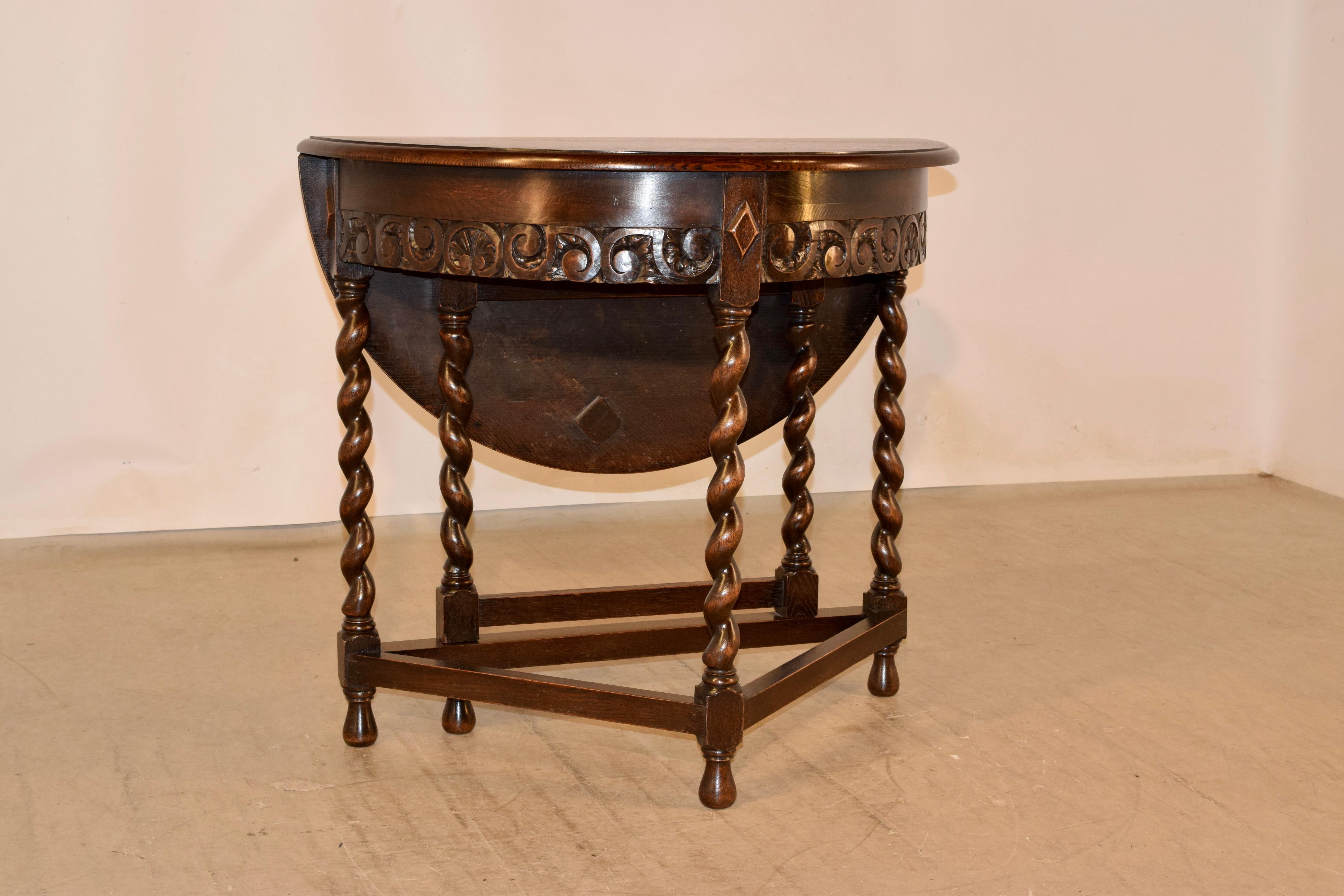 Late 19th century English oak Demi-lune table with a dropped leaf. The top is round when the leaf is raised and measures 33 inches in diameter. The top has a beveled edge and follows down to an apron with a hand carved bordered lower edge and is