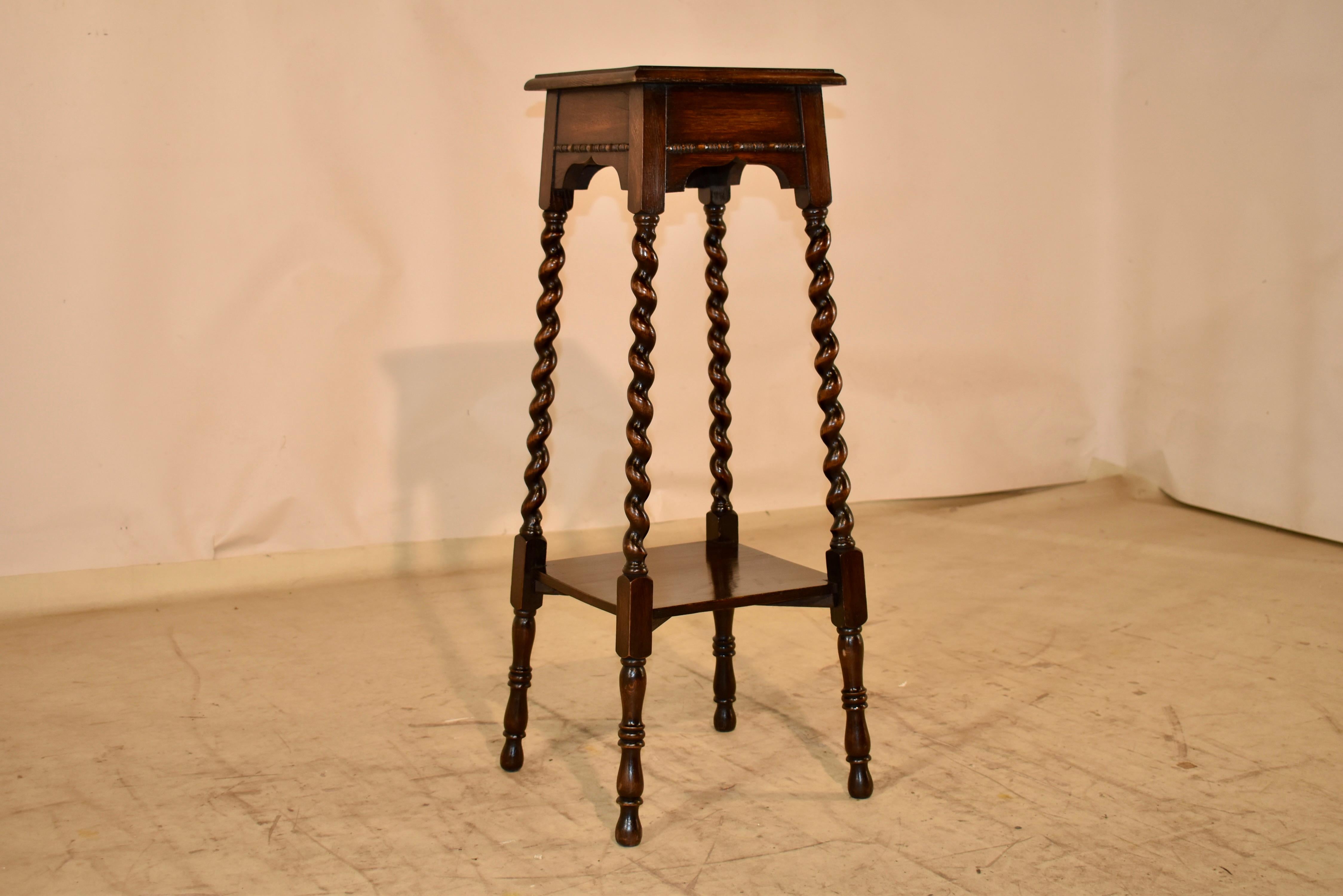Late 19th century English oak plant stand with two shelves. The top one is beveled around the edge and follows down to a scalloped apron with beading decoration and is supported on barley twist legs, joined by a bottom shelf and raised on tall