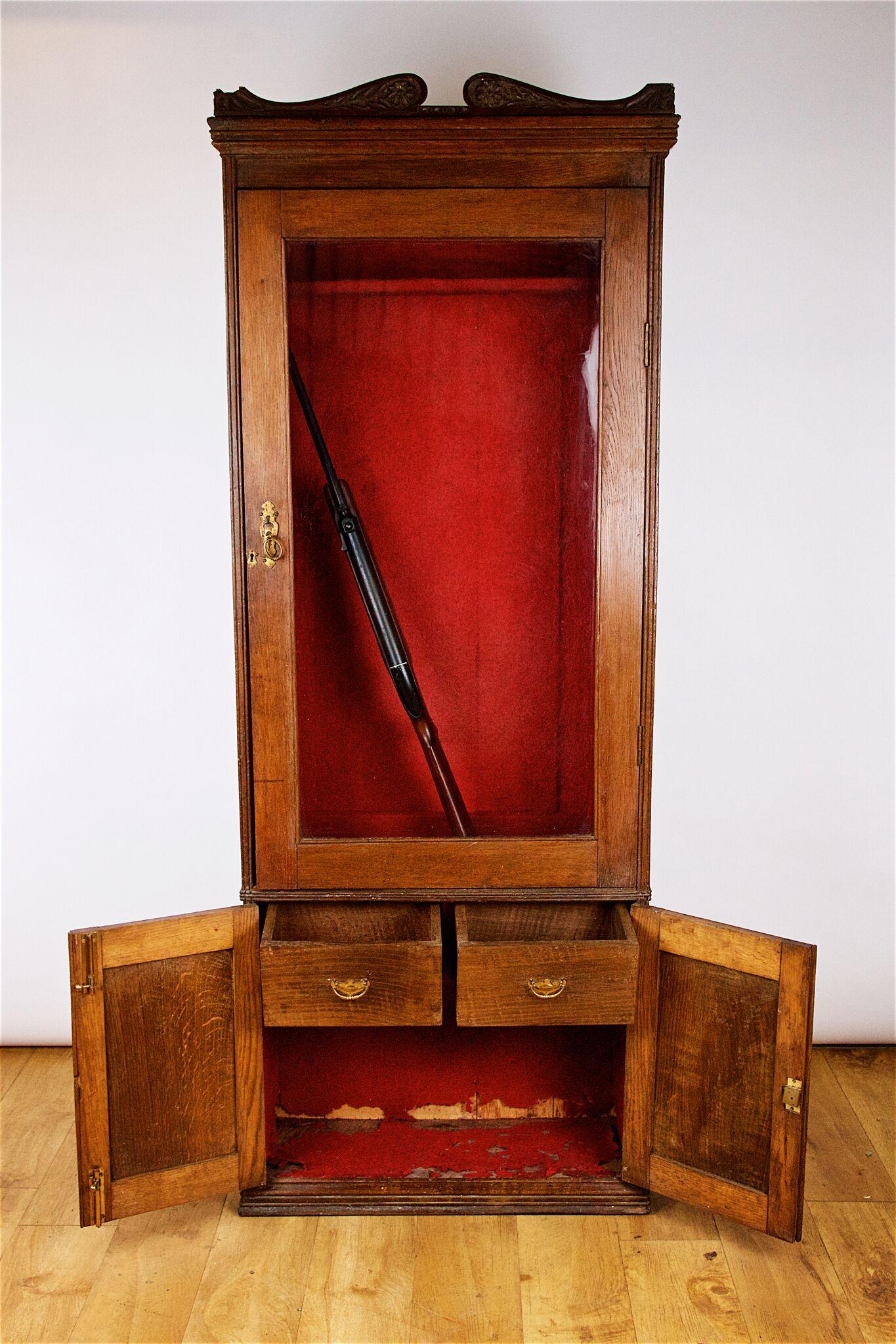 Late 19th century English oak gun cabinet to hold 6 guns with 2 internal drawers for cartridges, circa 1900. 
Possibly made by Army and Navy Stores, London.