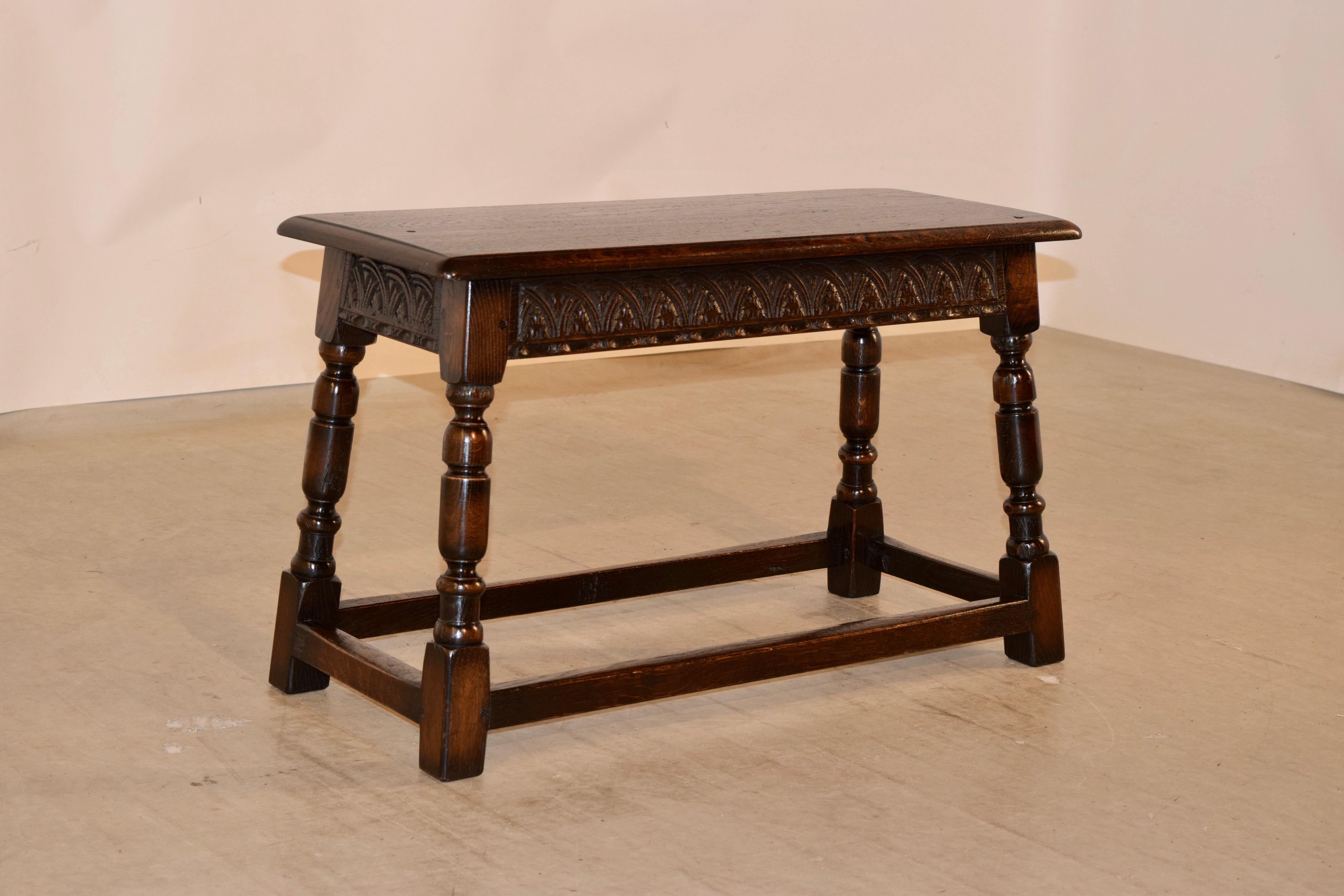 Late 19th century English oak joynt bench with a beveled edge around the top, following down to a hand carved decorated apron and splayed turned legs, joined by simple stretchers. Great size.